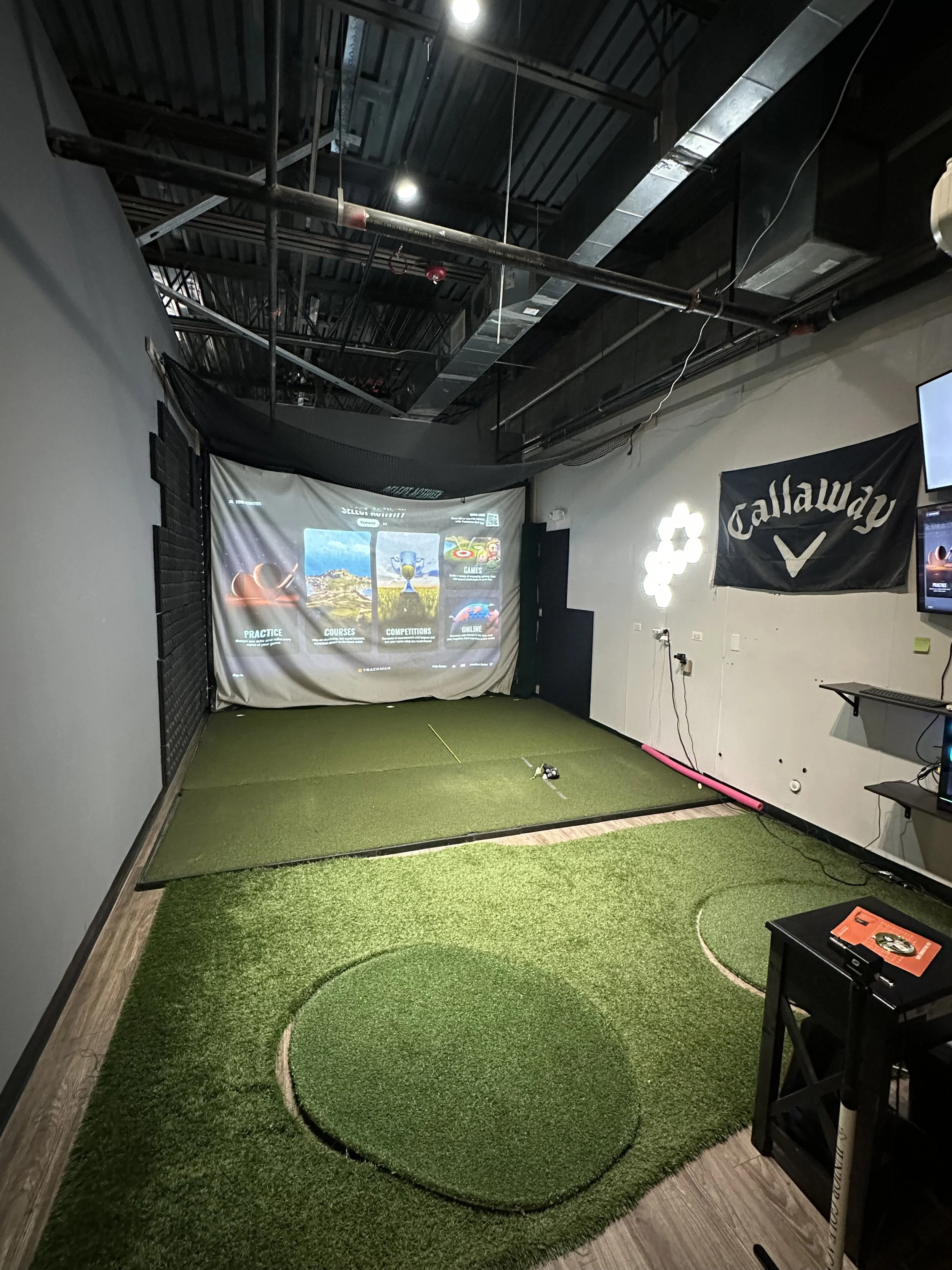 private indoor golf simulator with large screen and various golf mats