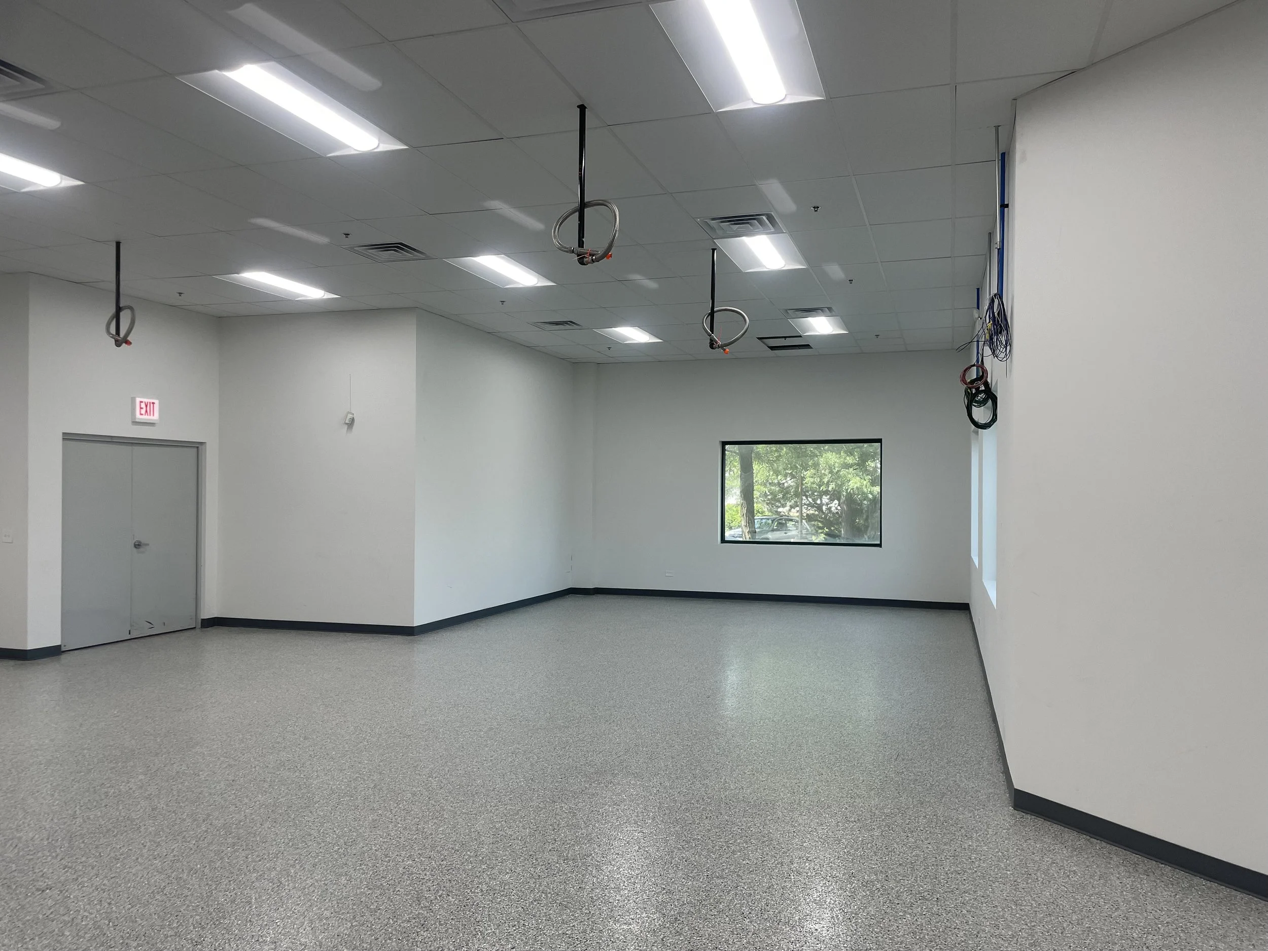 Interior space, white walls, white floors, bright lights, hanging electrical