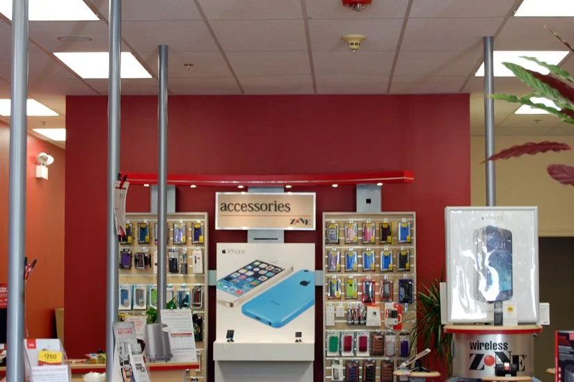 Verizon store interior, accessories display along the wall, red arc lights above display