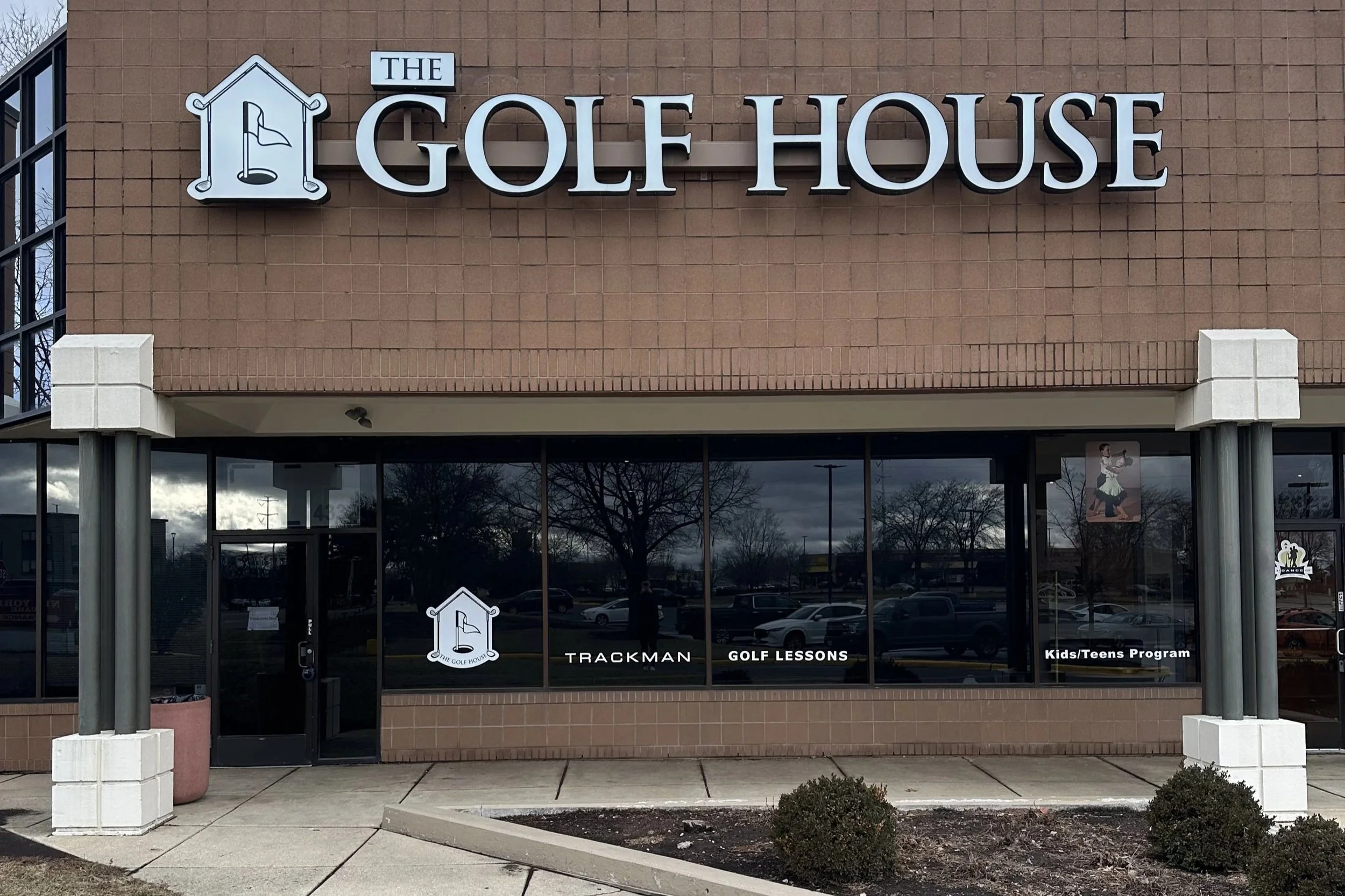 building exterior with The Golf House logo and sign above a series of windows
