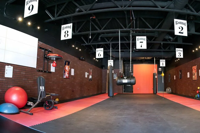 interior boxing gym, hanging bags in stations, red mats, weights