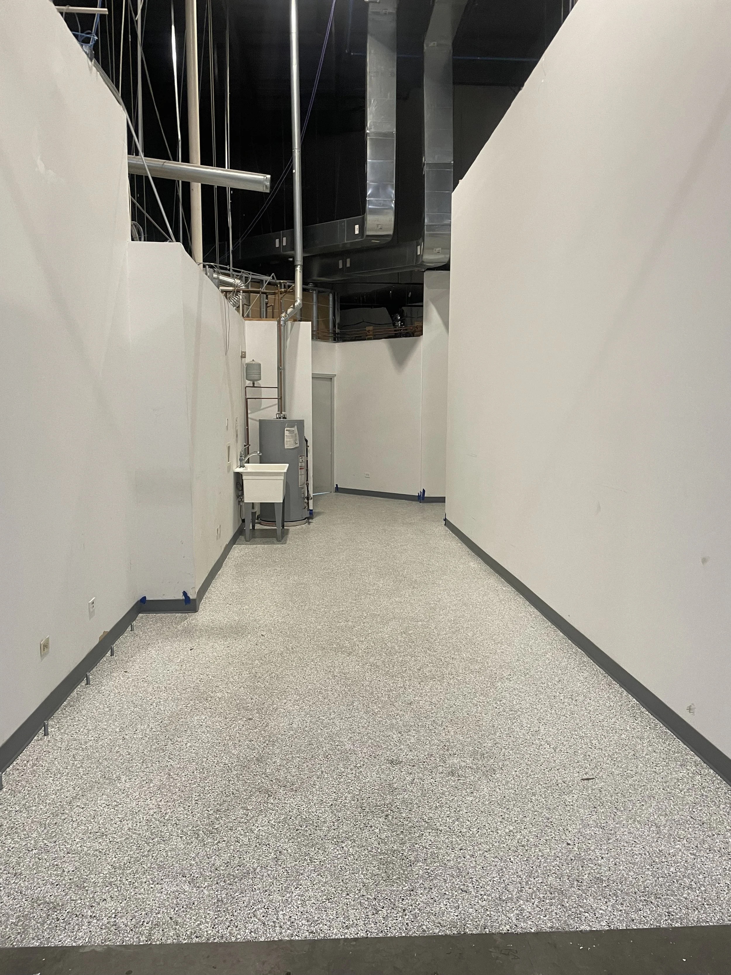 Interior industrial space, visible HVAC, white walls, open ceiling