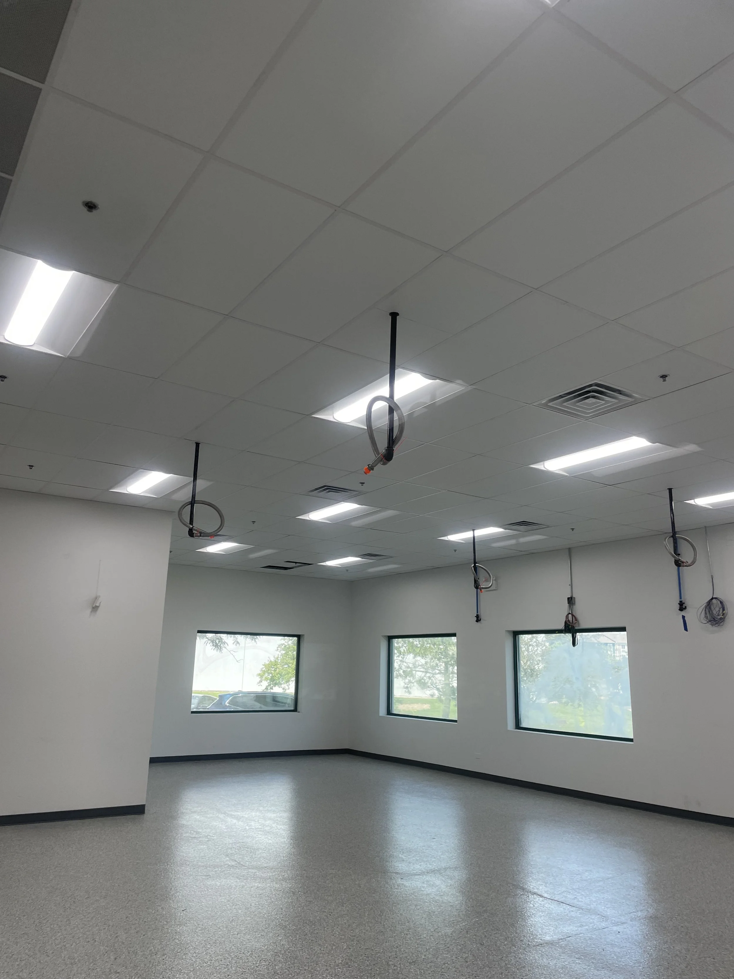 Interior space, white walls, white floors, bright lights, hanging electrical