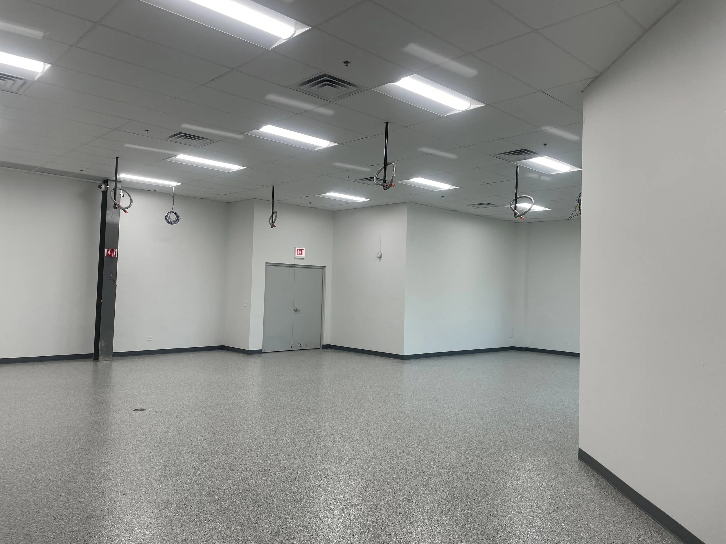 Interior space, white walls, white floors, bright lights, hanging electrical