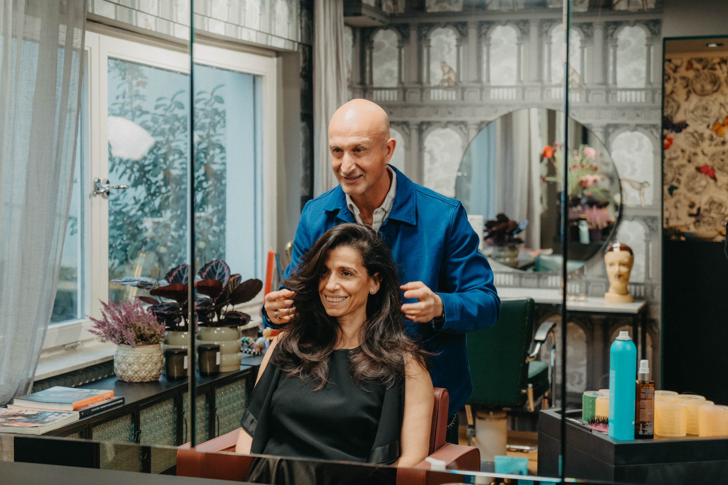 Ein Friseur schneidet einer Frau die Haare in einem Salon, beide lächeln und haben eine angenehme Atmosphäre.