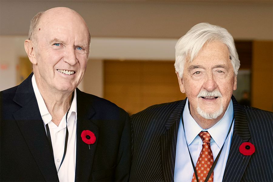 Group photo of Keith Gordon (left) and Michael Baillargeon (right) smiling for the camera while attending the October 2024 Vision Health Conference. Both are wearing light collared shirts and black blazers, with poppies adorning their left lapels.