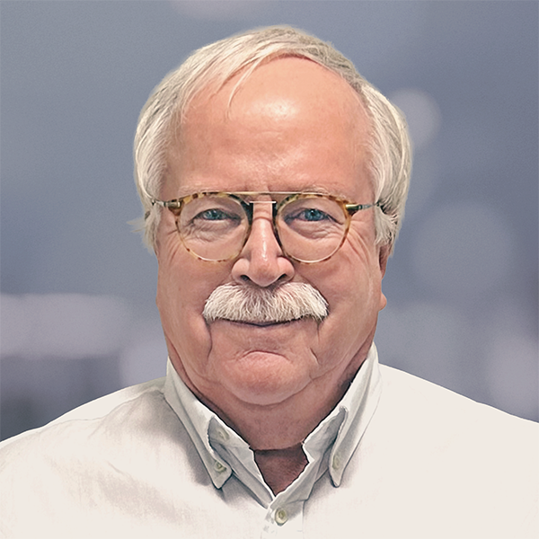 Portrait of a smiling James Hall wearing a white collared shirt.