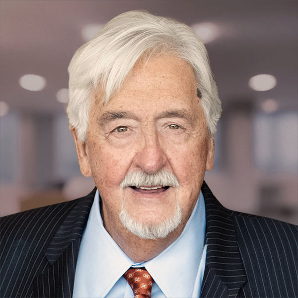 Portrait of a smiling Michael Baillargeon wearing an orange tie, white collared shirt and a black pinstriped blazer.