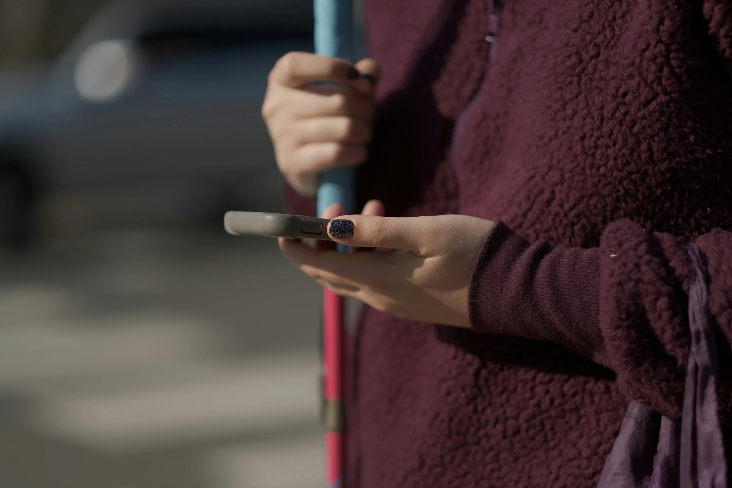 A visually impaired woman, expressing the use of technology for the blind and visually impaired while riding public transportation and going for a walk. She is using text-to-speech, an assistive technology that reads what is on her screen.