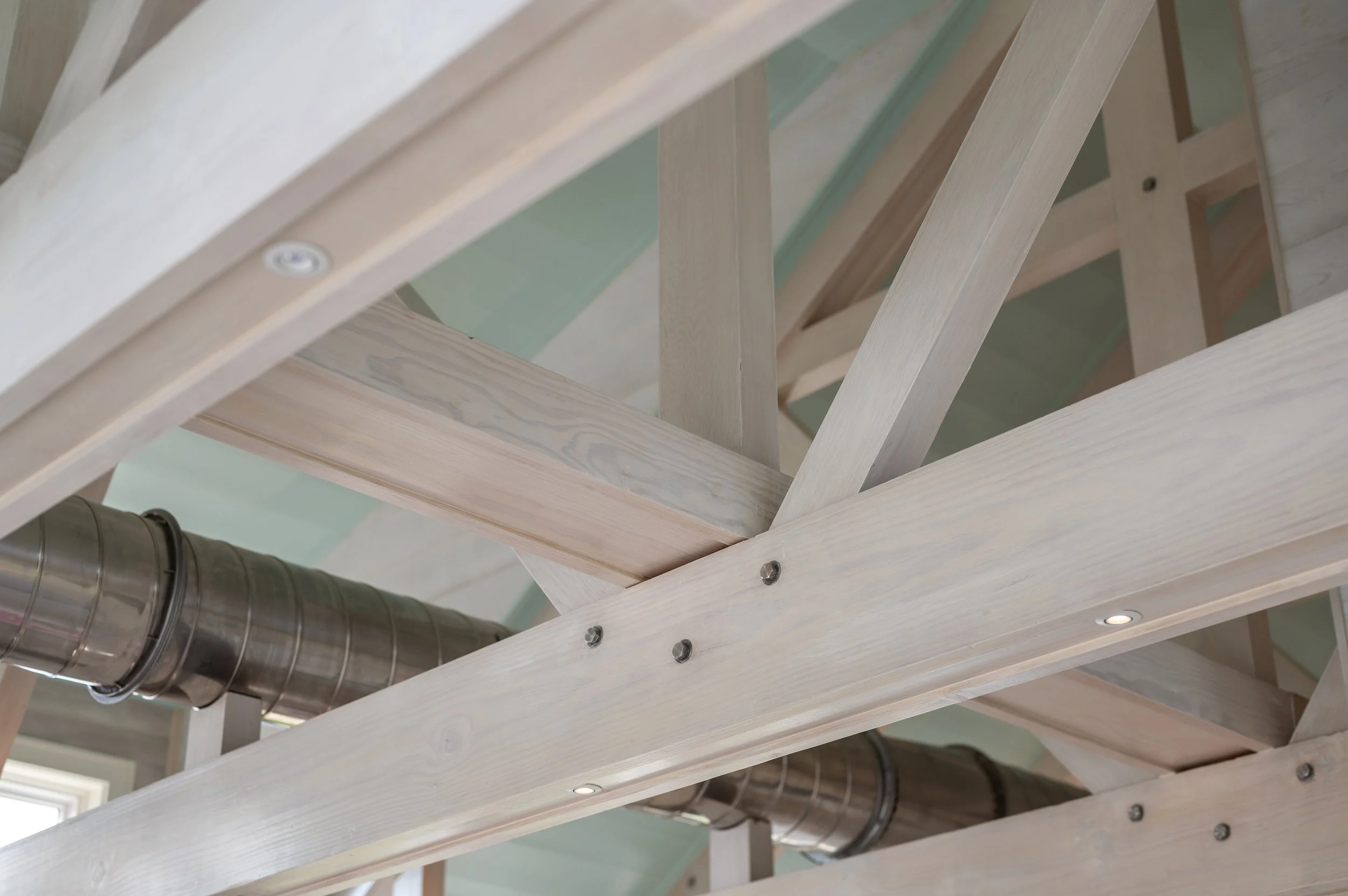 Construction framing with wooden beams and metal ductwork in a building under construction.