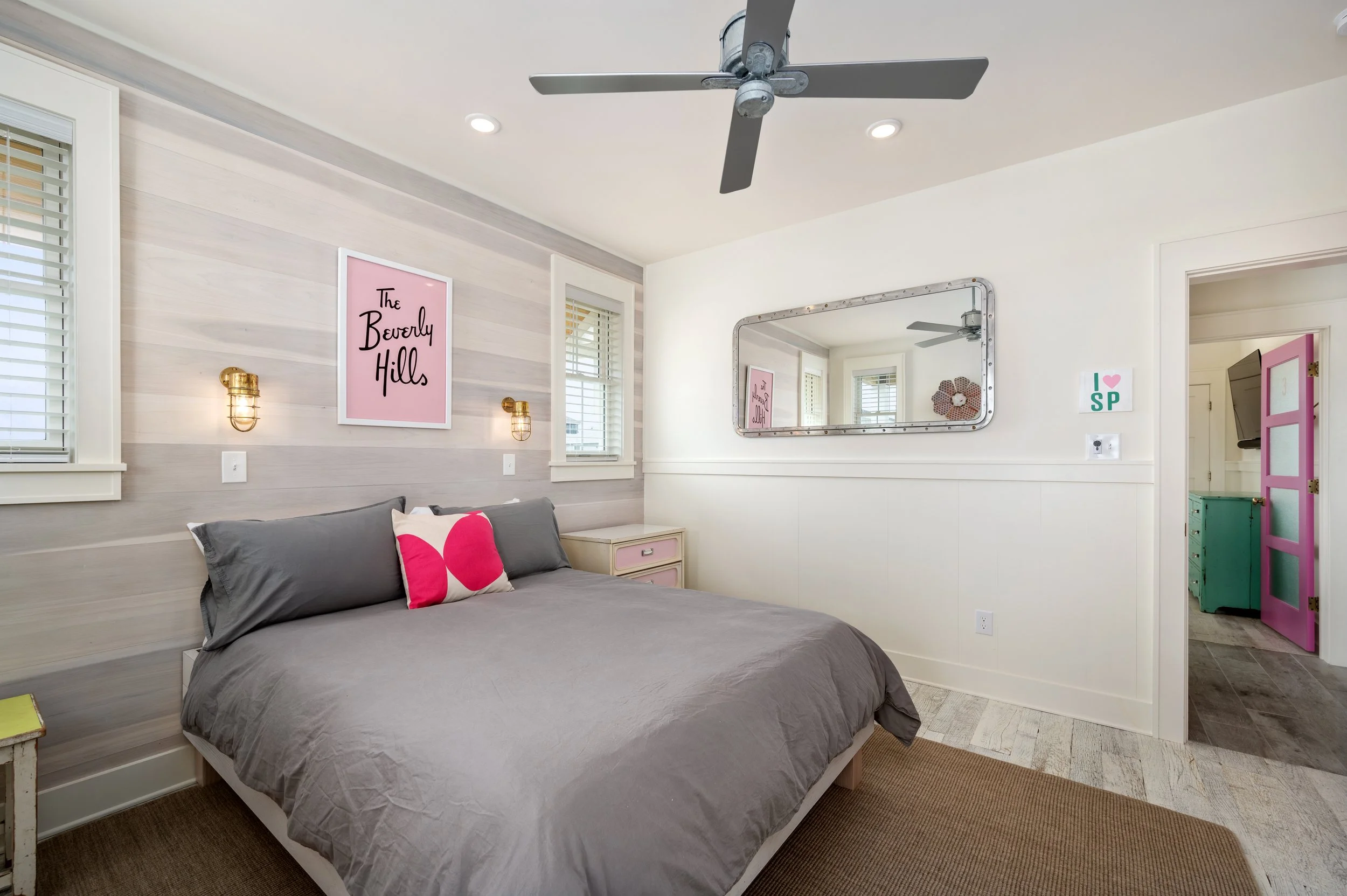 Bedroom with gray bedding, pink decor, and a large mirror on the wall