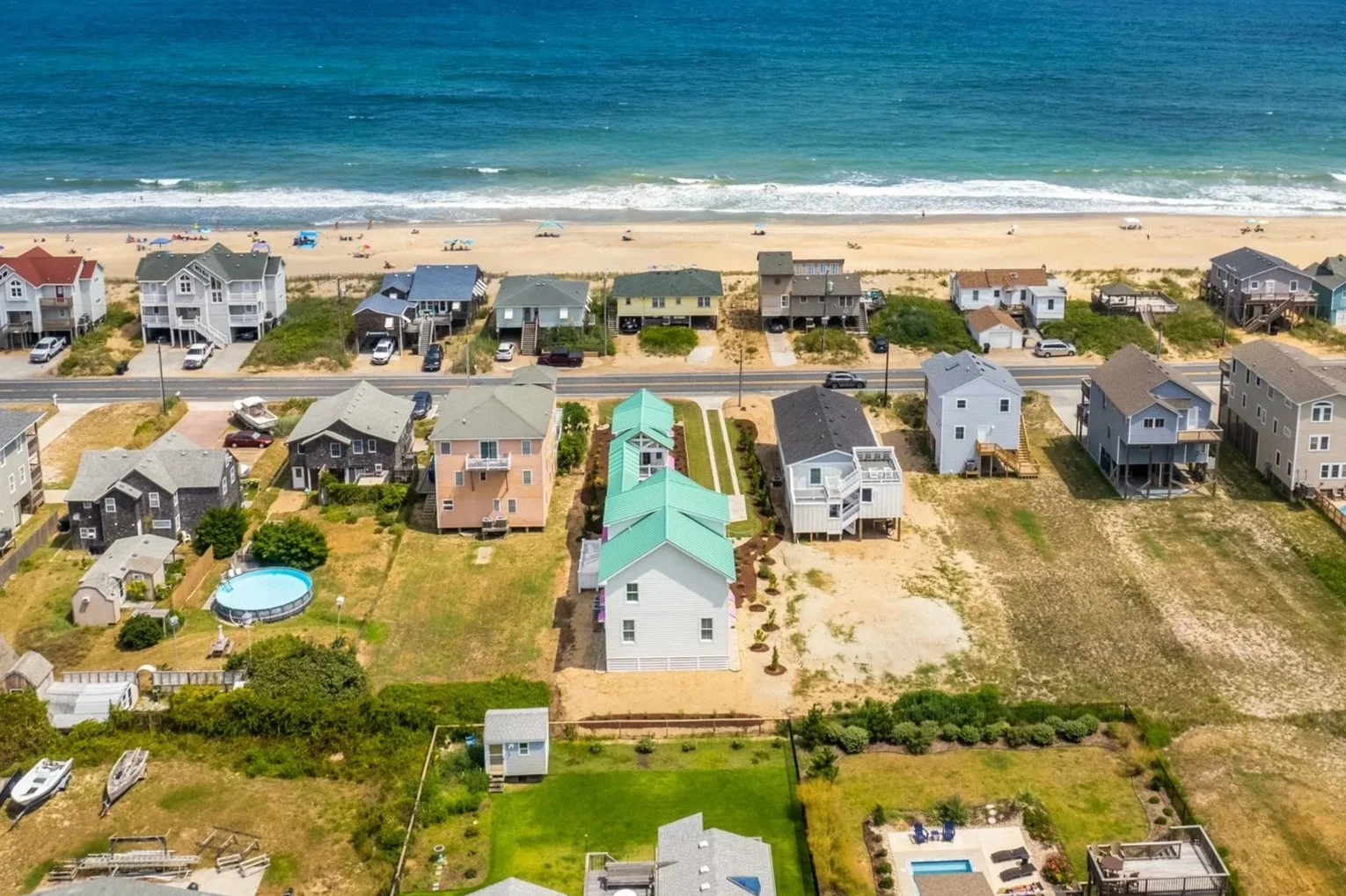 Aerial view of a coastal neighborhood with houses, a beach, and the ocean in the background.