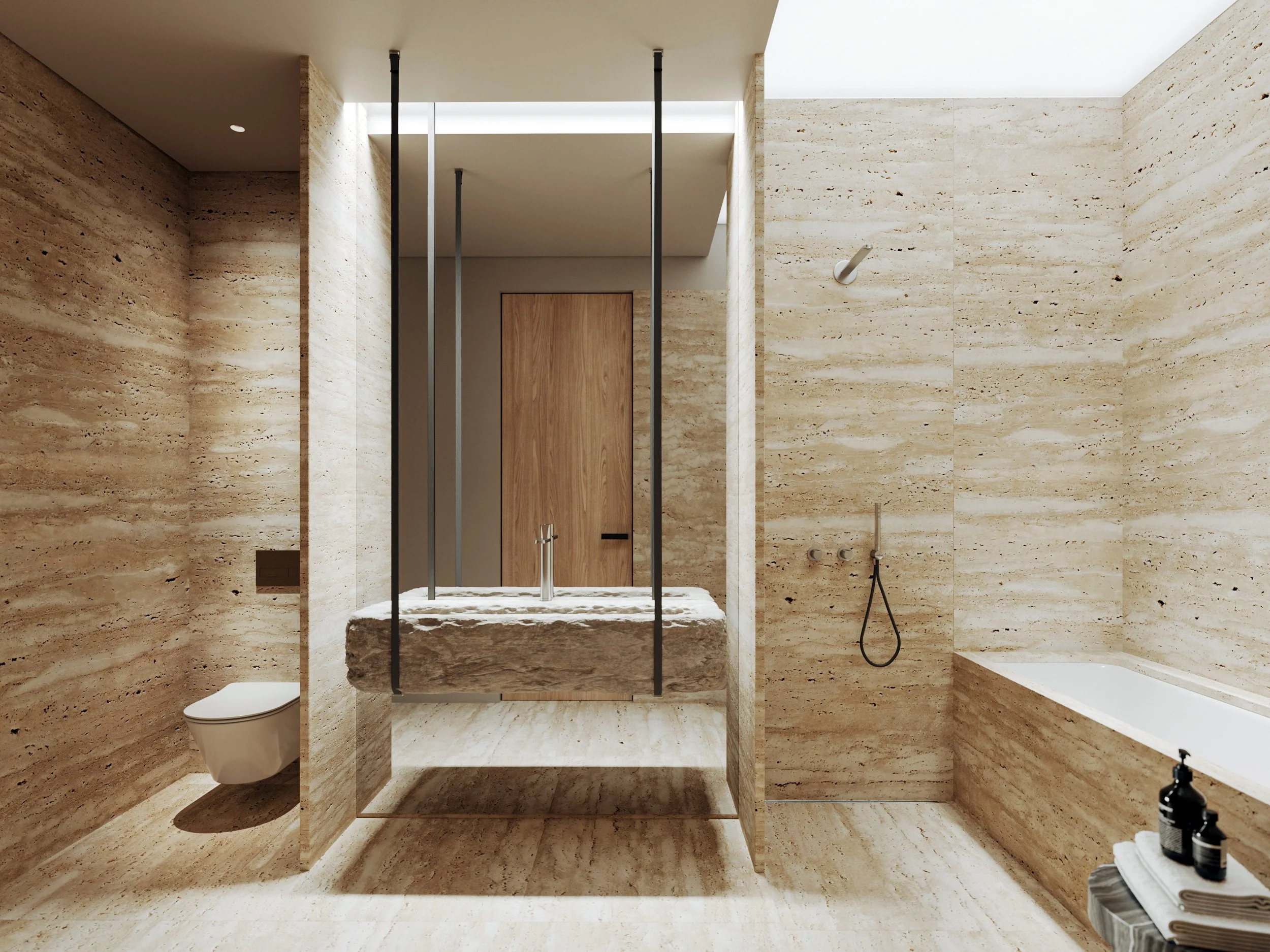 Modern bathroom with beige marble walls and floor, featuring a wall-mounted toilet, a freestanding bathtub, a stone sink with a chrome faucet, and a wall-mounted shower head and hand shower. Wooden door in the background and some black bottles on a side table.