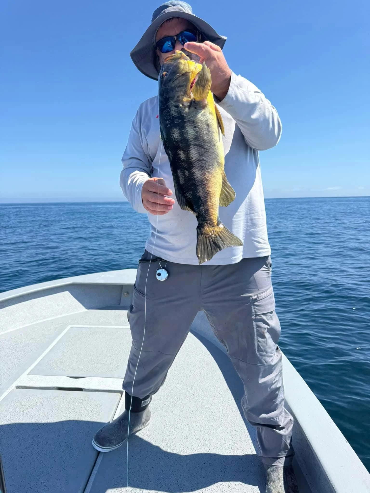 Angler holding a large fish on a boat during a Cedros sportfishing trip.