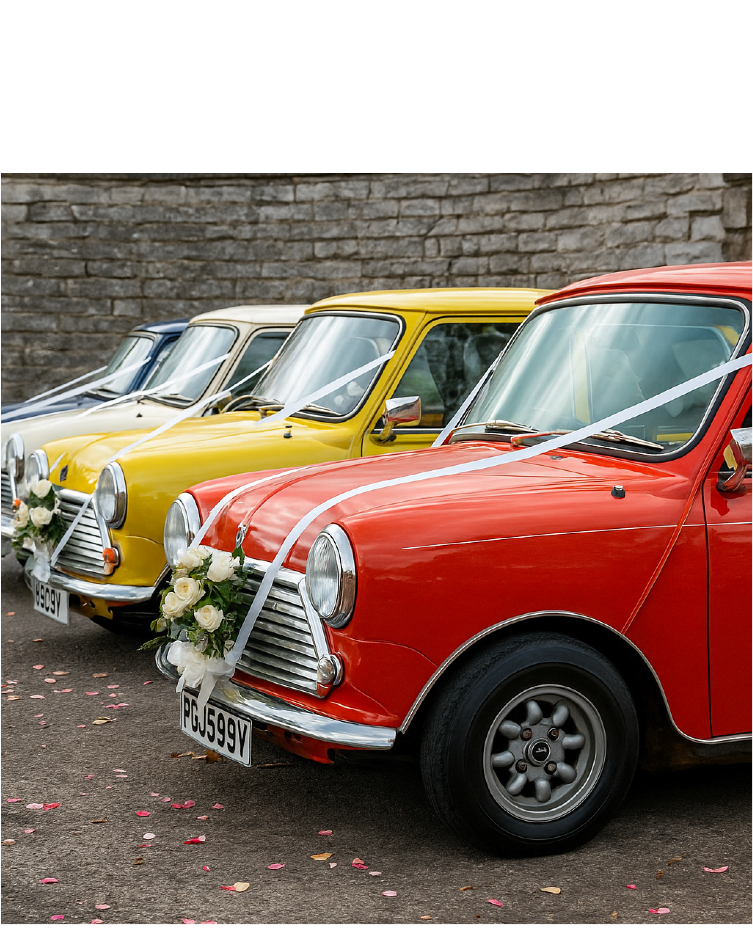 Four vintage cars decorated with white ribbons and flowers, parked side by side, likely for a wedding.