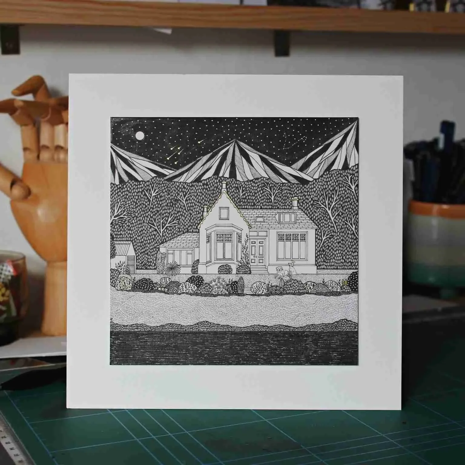 A black-and-white line drawing of a house set in a landscape with mountains, trees, and a body of water in the foreground, under a starry night sky with a moon.