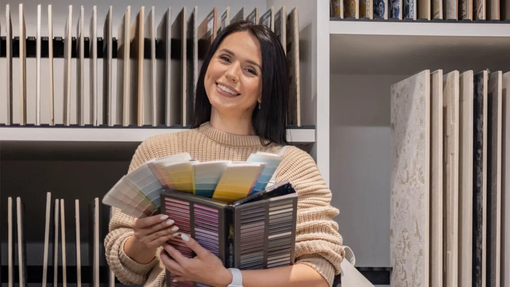 A woman holds textile swatches and smiles