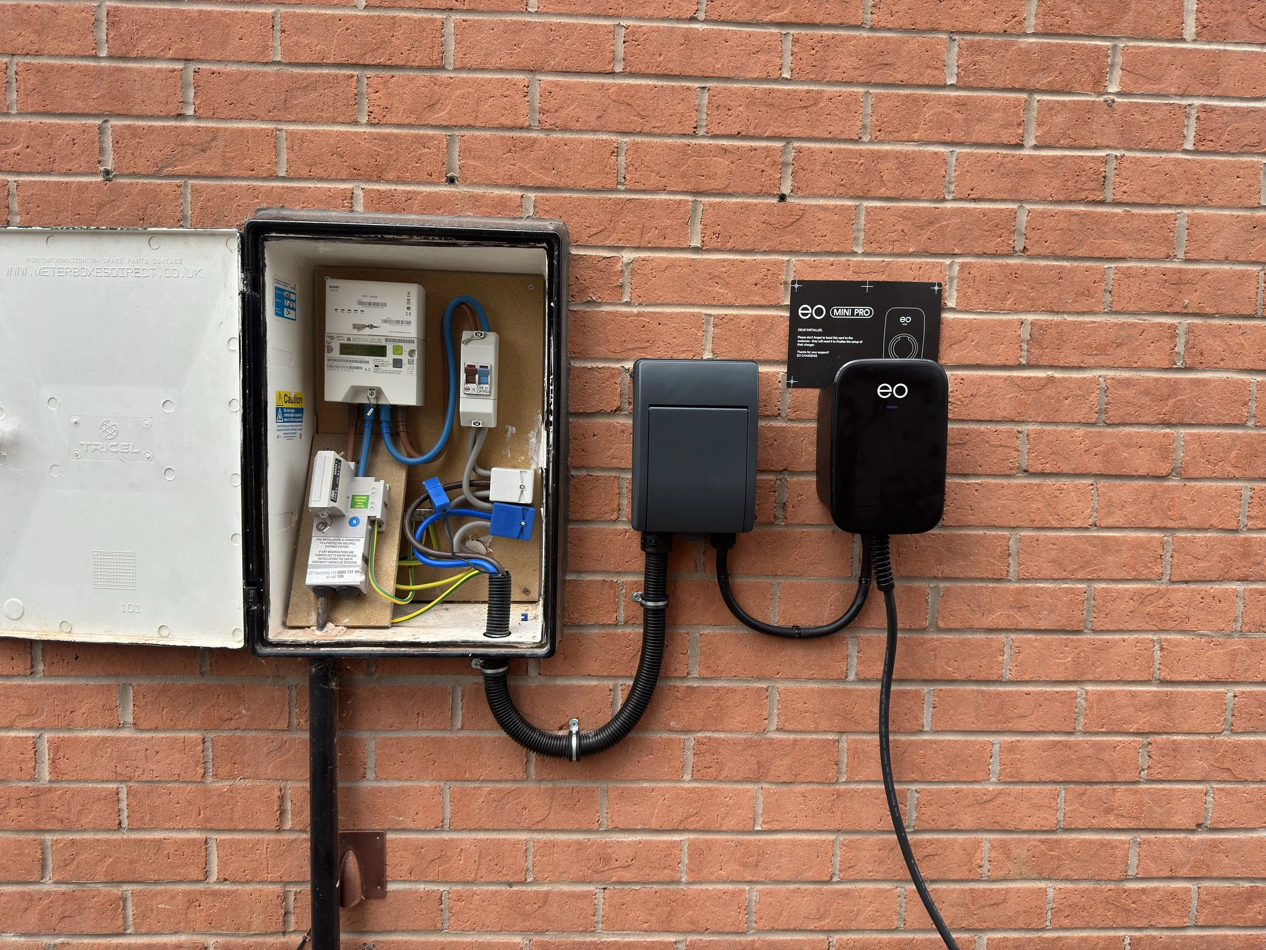 Electrical meter box and smart energy monitoring devices mounted on a brick wall.