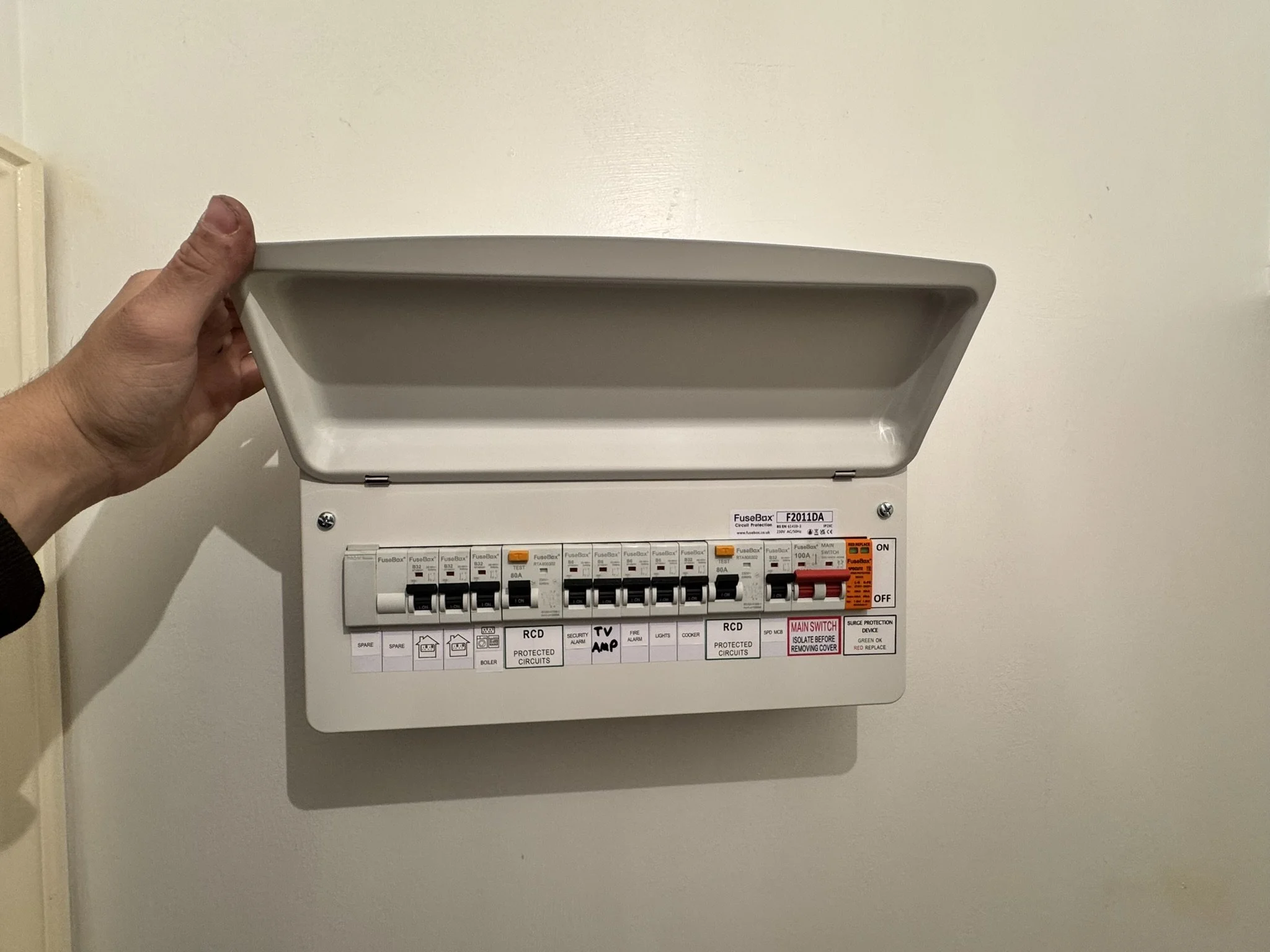 Empty electrical breaker box with cover partially open mounted on a wall.