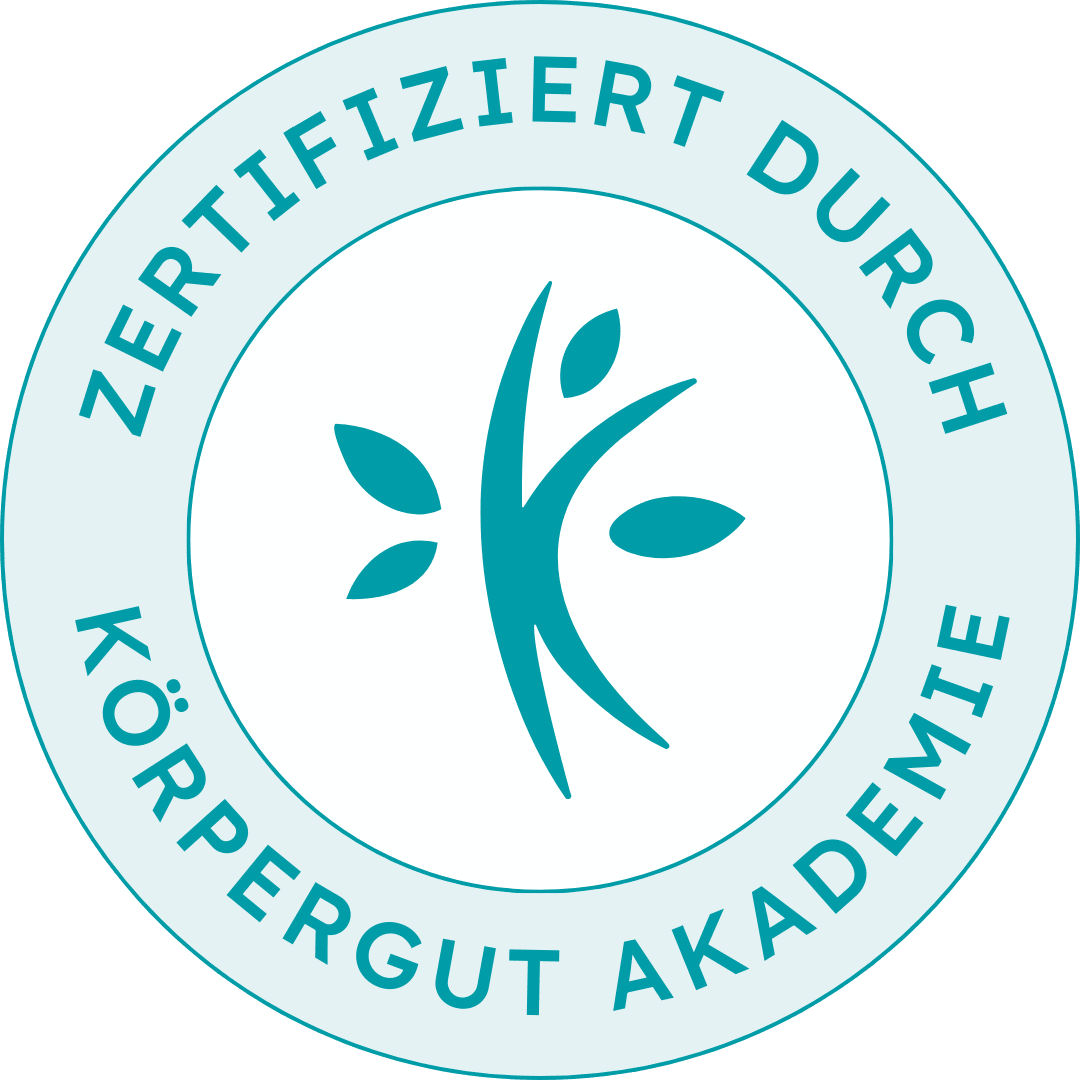 A circular badge with the German phrase 'Zertifiziert Durch Körperegut Akademie' around the edge and a stylized tree with several leaves in the center, all in shades of teal and white.