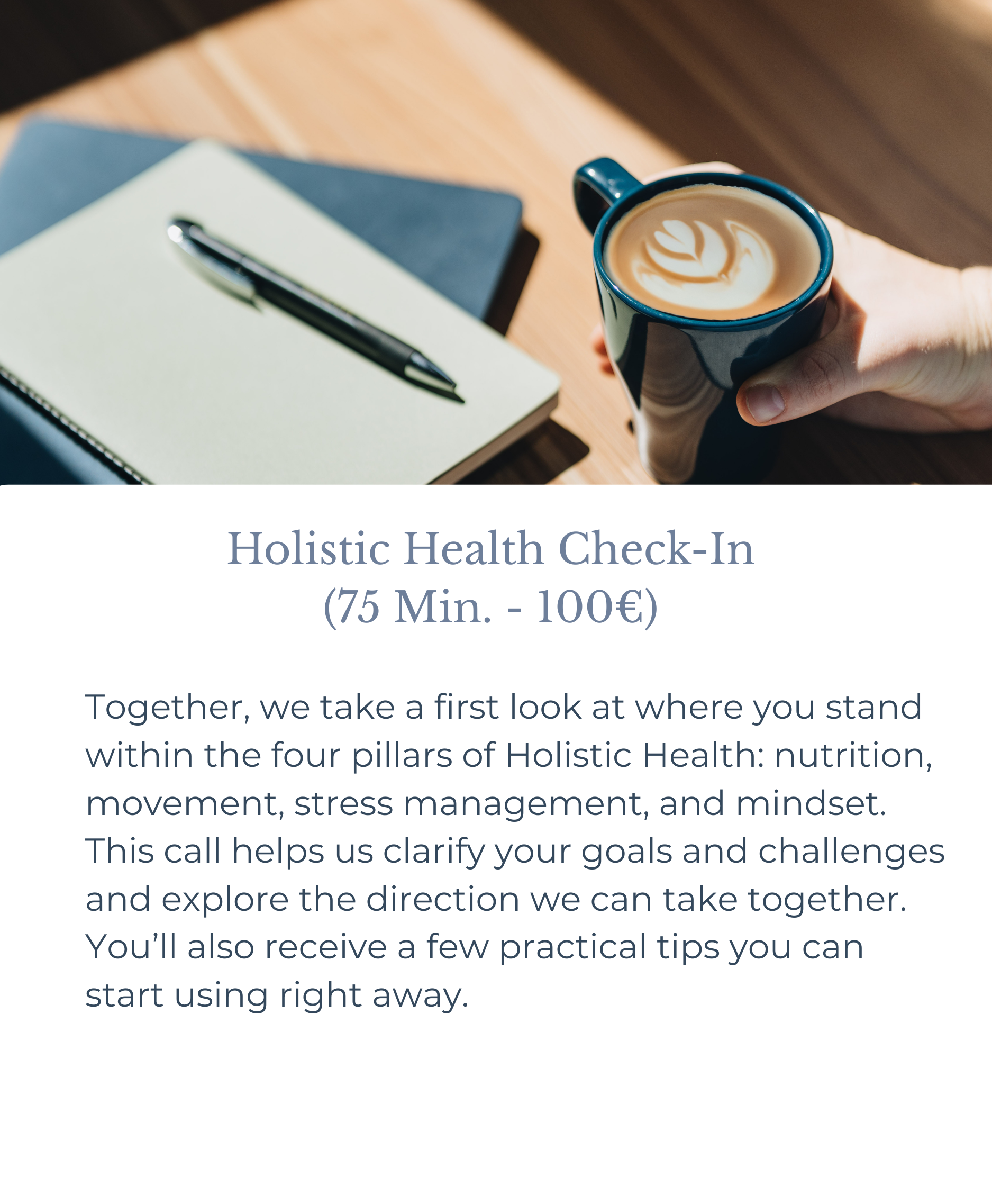 A hand holding a blue mug with latte art, a closed notebook with a pen on top, on a wooden table in sunlight.