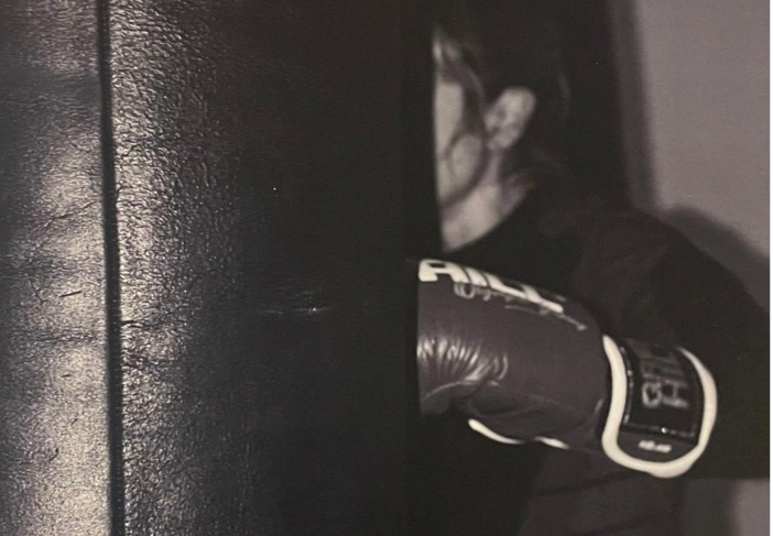 A black punching bag and a wrapped boxing glove resting on the ground.