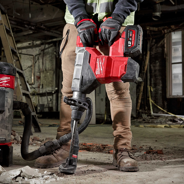 Person using a Milwaukee cordless jackhammer on a construction site.