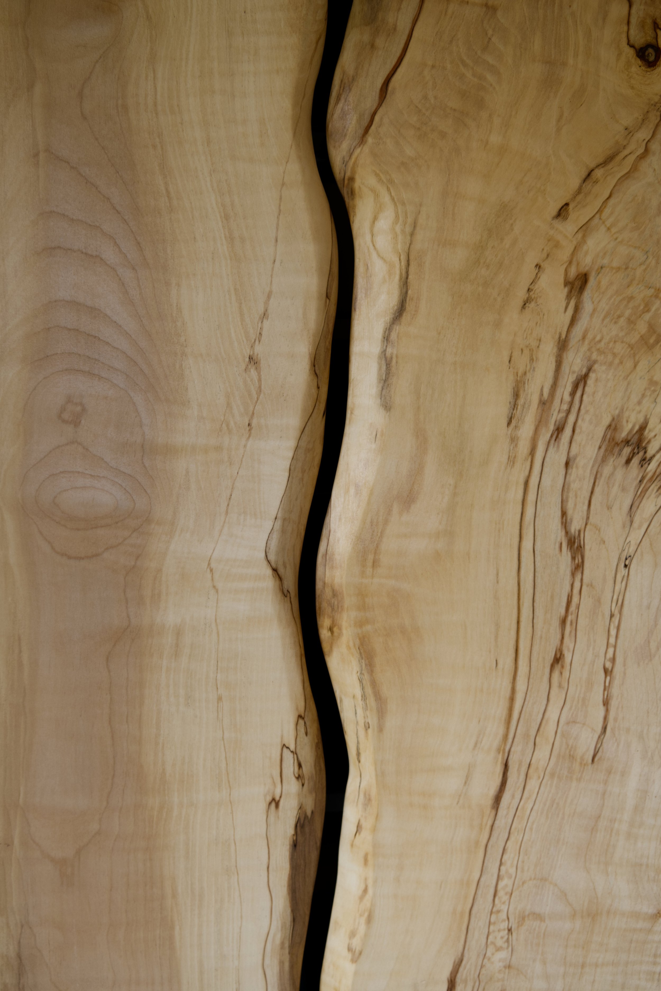 Close-up of a wooden surface with a dark, irregular crack in the middle.