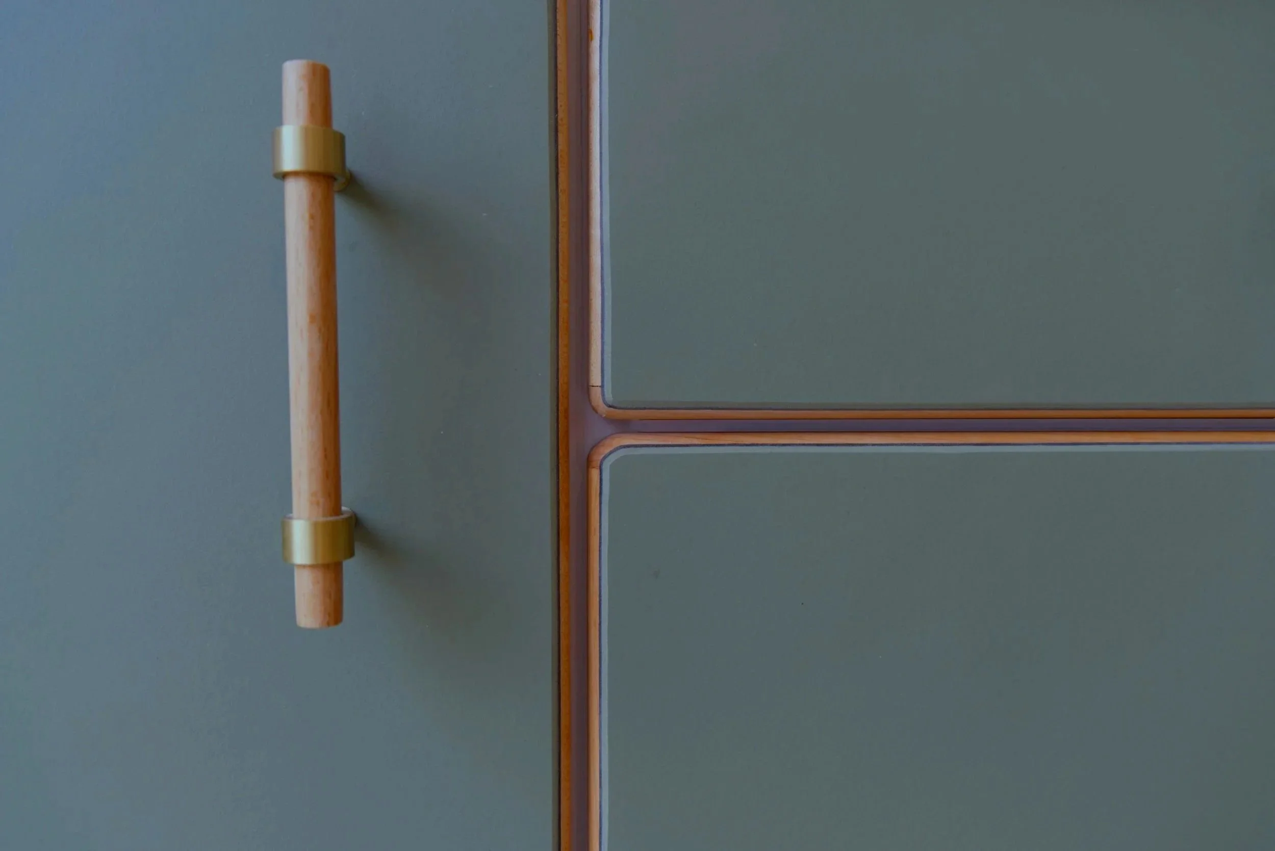 Close-up of a door handle on a green cabinet with orange trim.