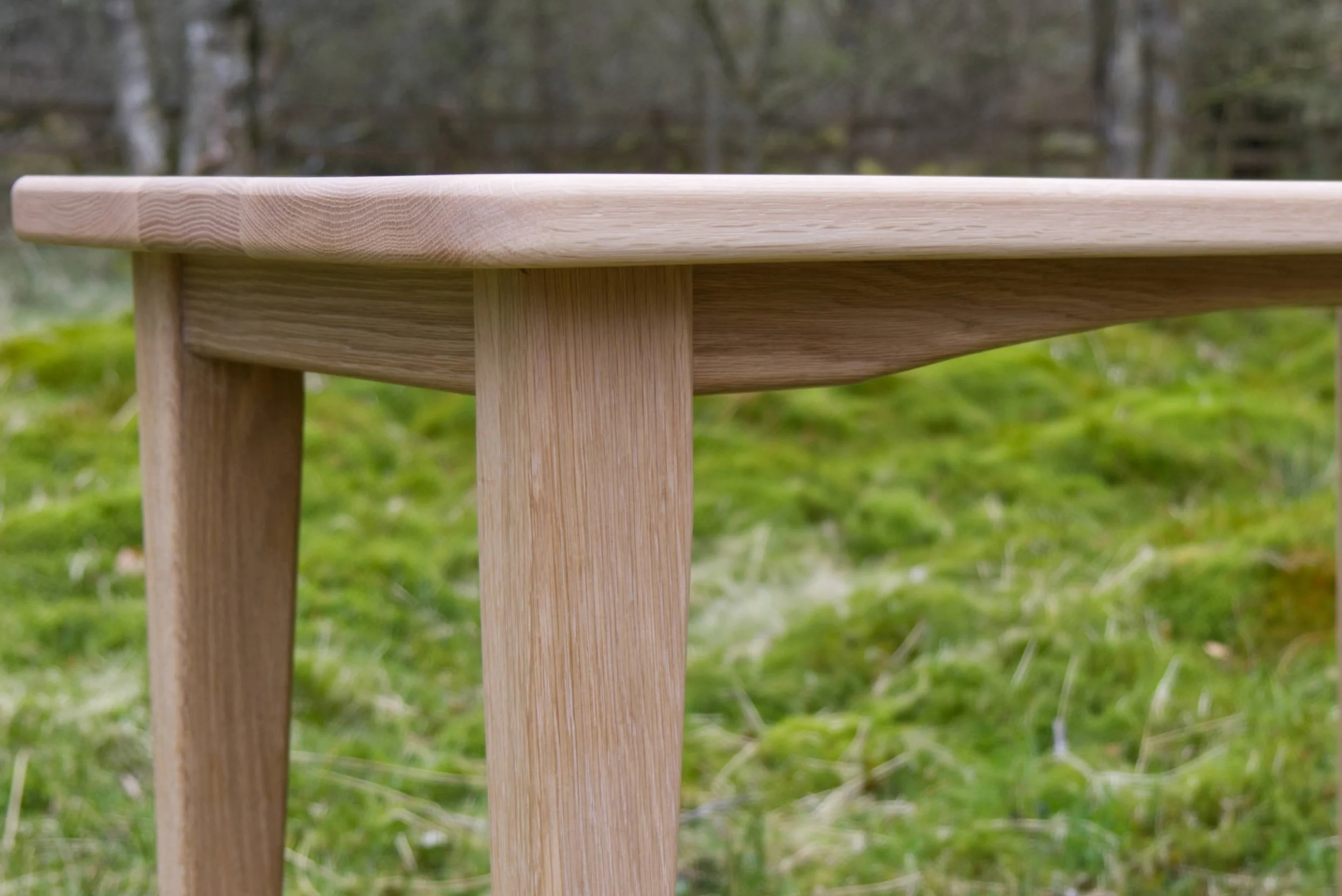 Close-up of a wooden table outdoors with a grassy background.