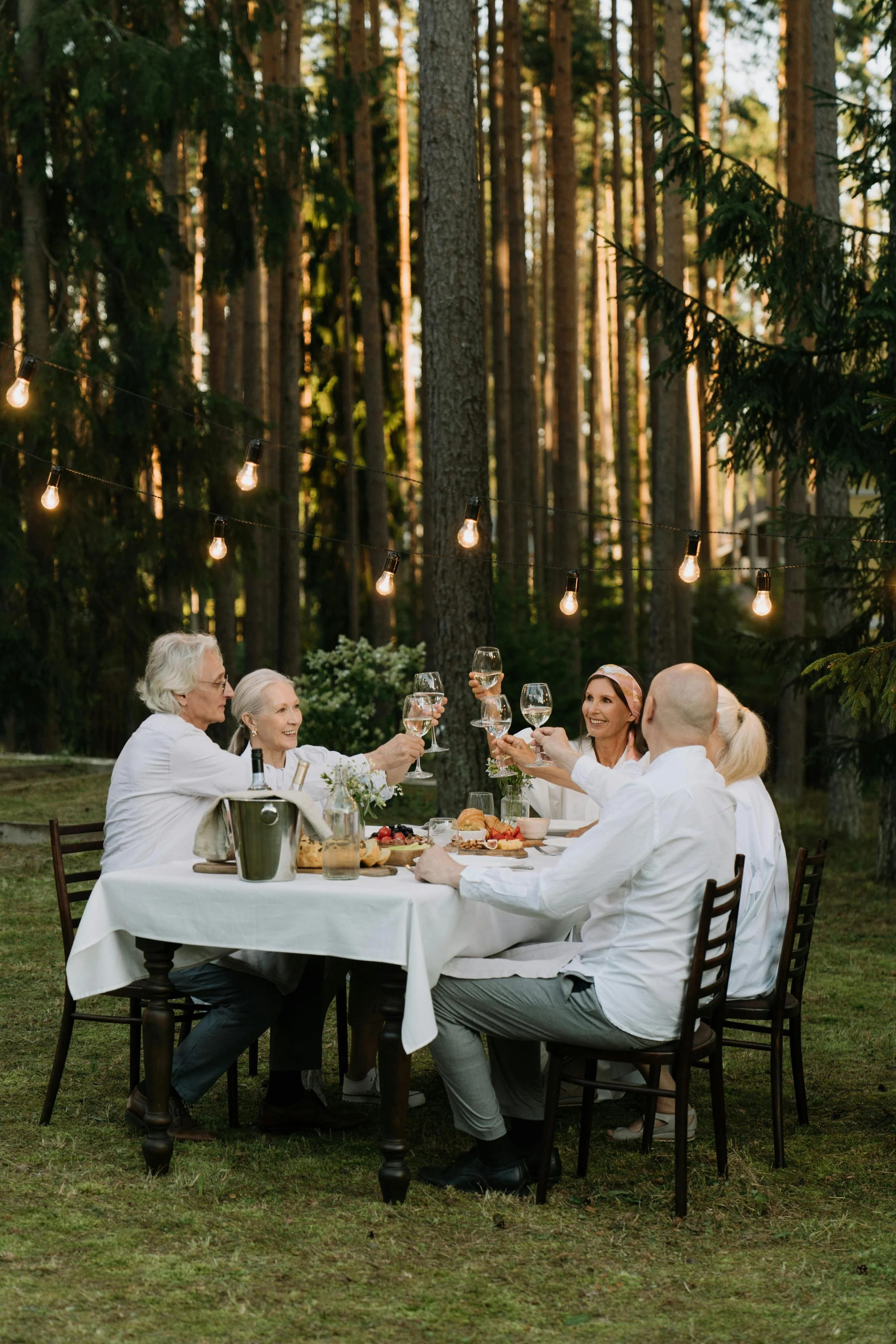 Group of middle-aged friends toast their wine glasses as they enjoy an al fresco dinner in Tuscany, Italy