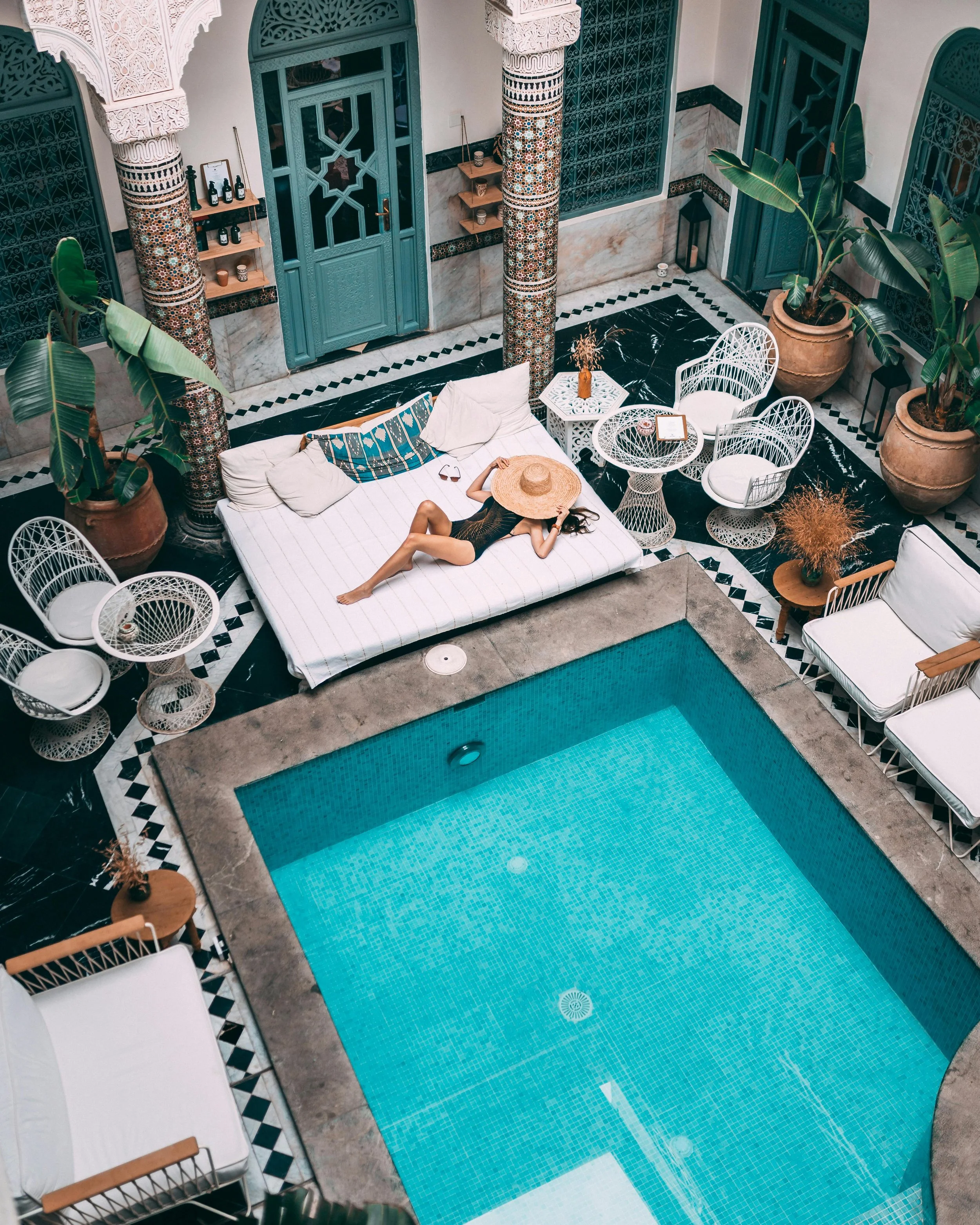 A woman lounges poolside in a gorgeous courtyard of a luxury riad in Morocco