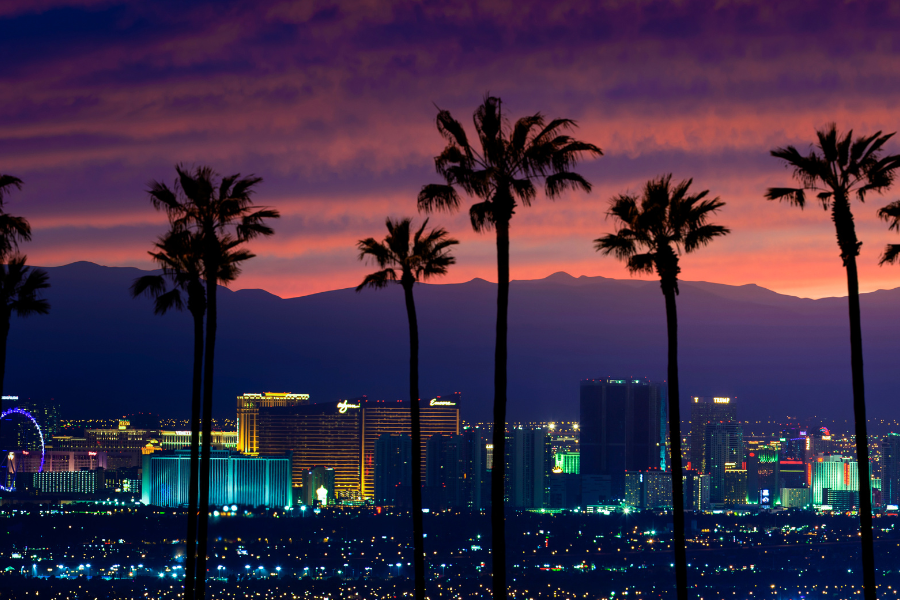 The Las Vegas Strip at dusk, with palm trees silhouetted against a vibrant sky