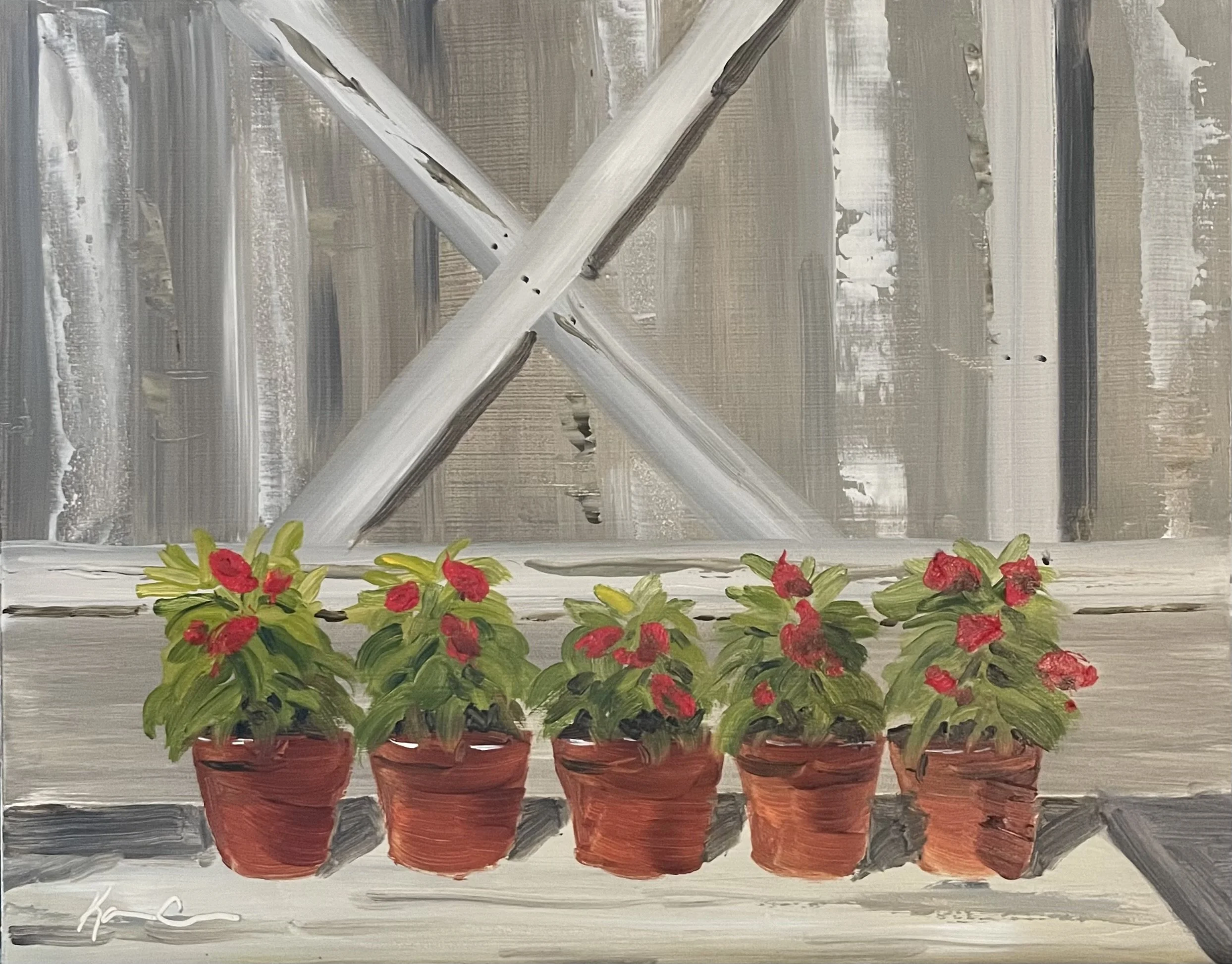 A row of five potted plants with pink flowers, placed on a flat surface in front of a painted wooden window frame.