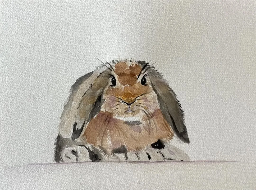 Watercolor painting of a cute brown rabbit with long ears, sitting against a plain white background.