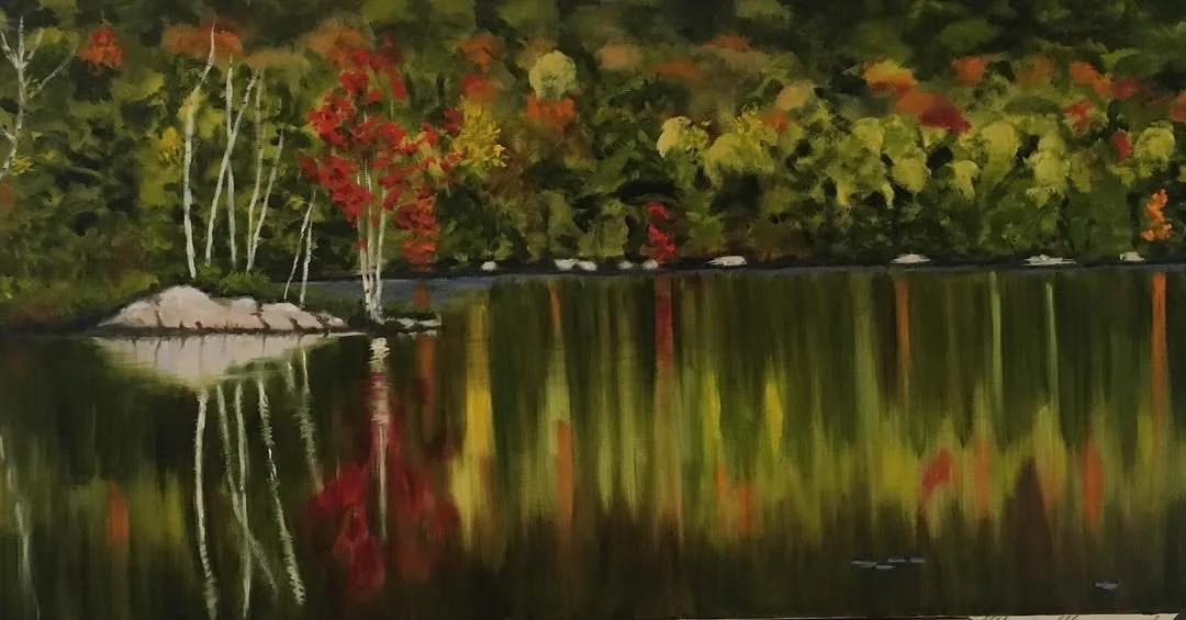 An oil painting of a lake surrounded by trees with fall foliage, reflecting the colorful leaves in the water.