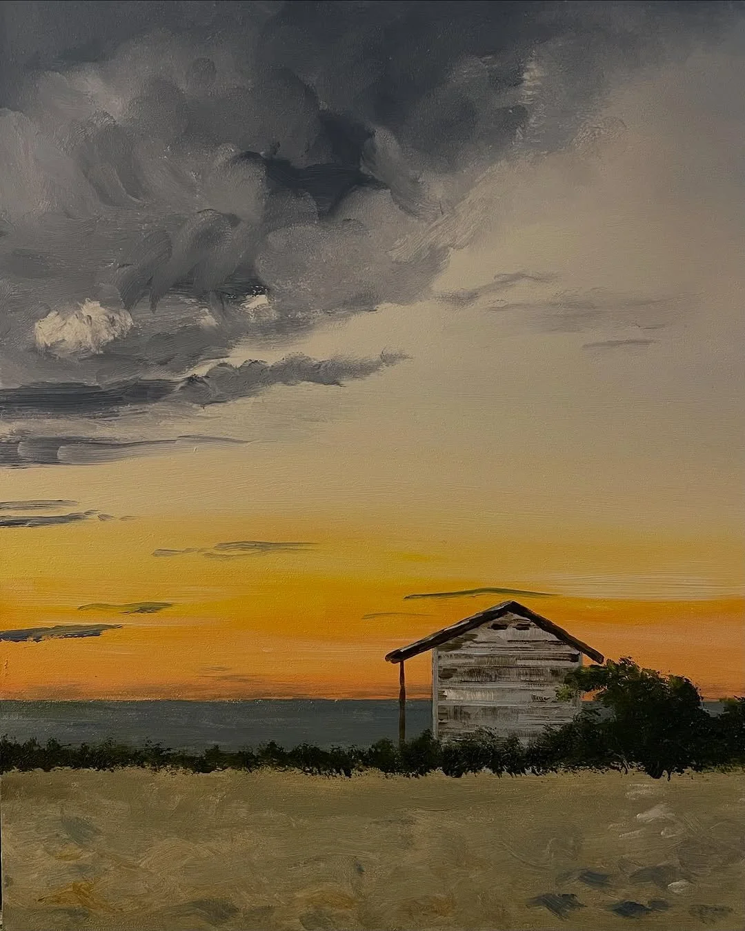 Painting of a sunset over water with dark clouds and a small, weathered house surrounded by bushes in the foreground.
