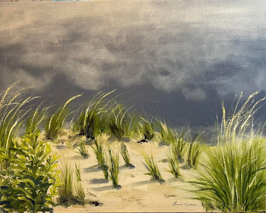 Painting of a sandy beach with green grass and plants under a dark, cloudy sky.
