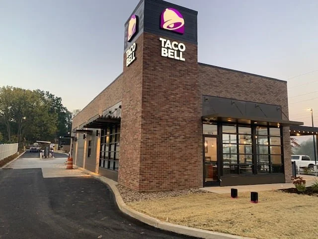 Taco Bell restaurant with brick exterior and a lit sign on top displaying the Taco Bell logo and name.