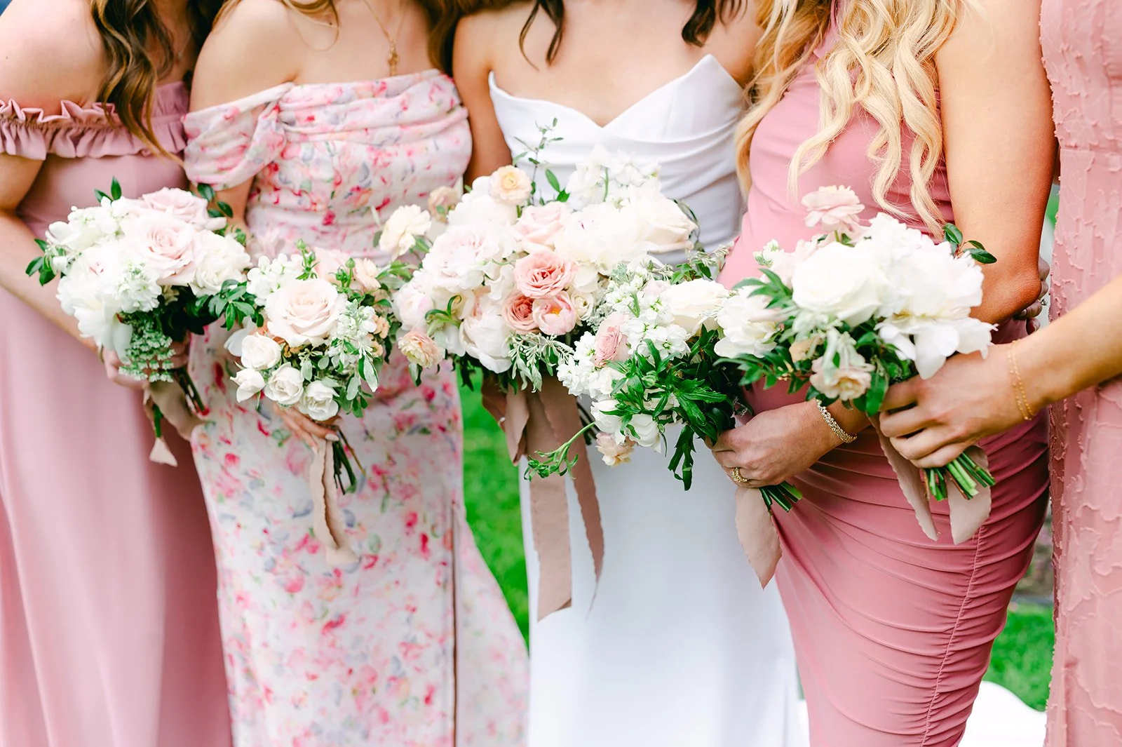 Group of women holding bouquets of pink and white flowers at a wedding