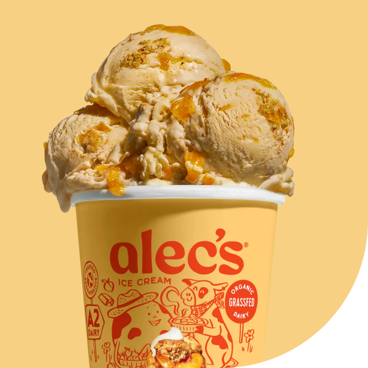 A yellow cup of Alec's ice cream with three scoops of vanilla topped with caramel sauce.