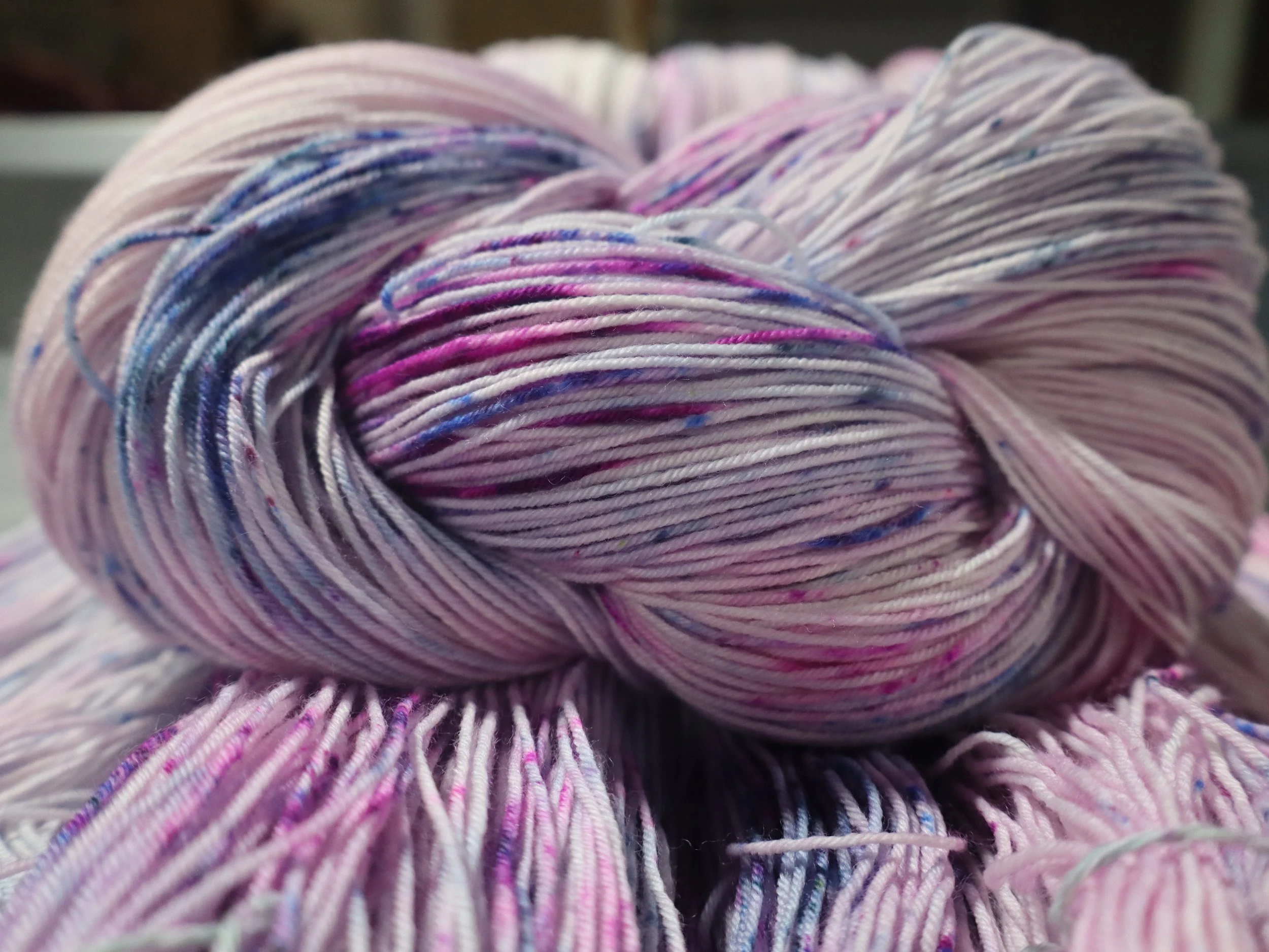 Close-up of a skein of pastel-colored yarn with shades of pink, purple, and blue.
