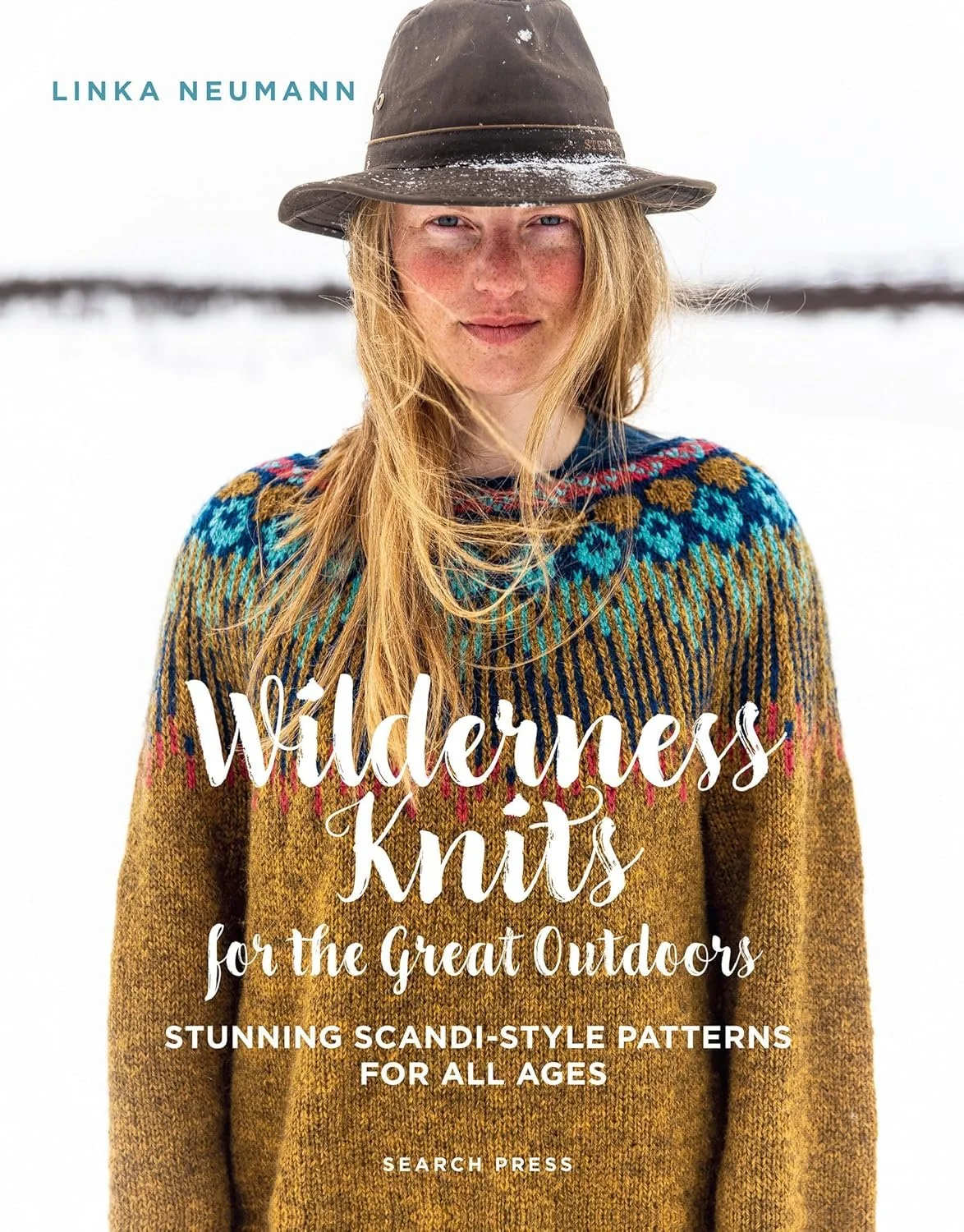 Woman in a hat with an ochre and turquoise handknit sweater.
