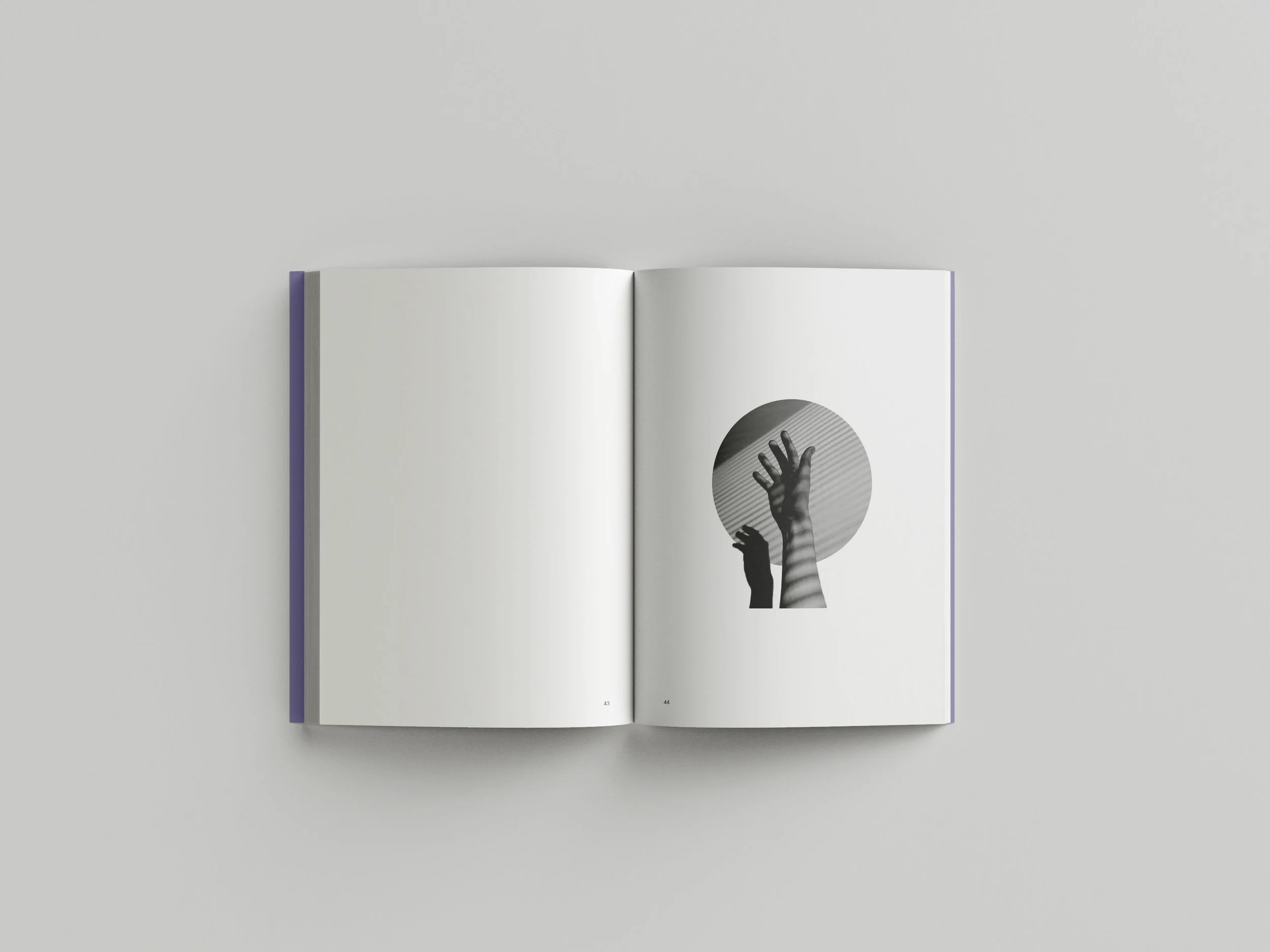 Open book with black and white illustration of two hands reaching towards a circular shape with shadow patterns.
