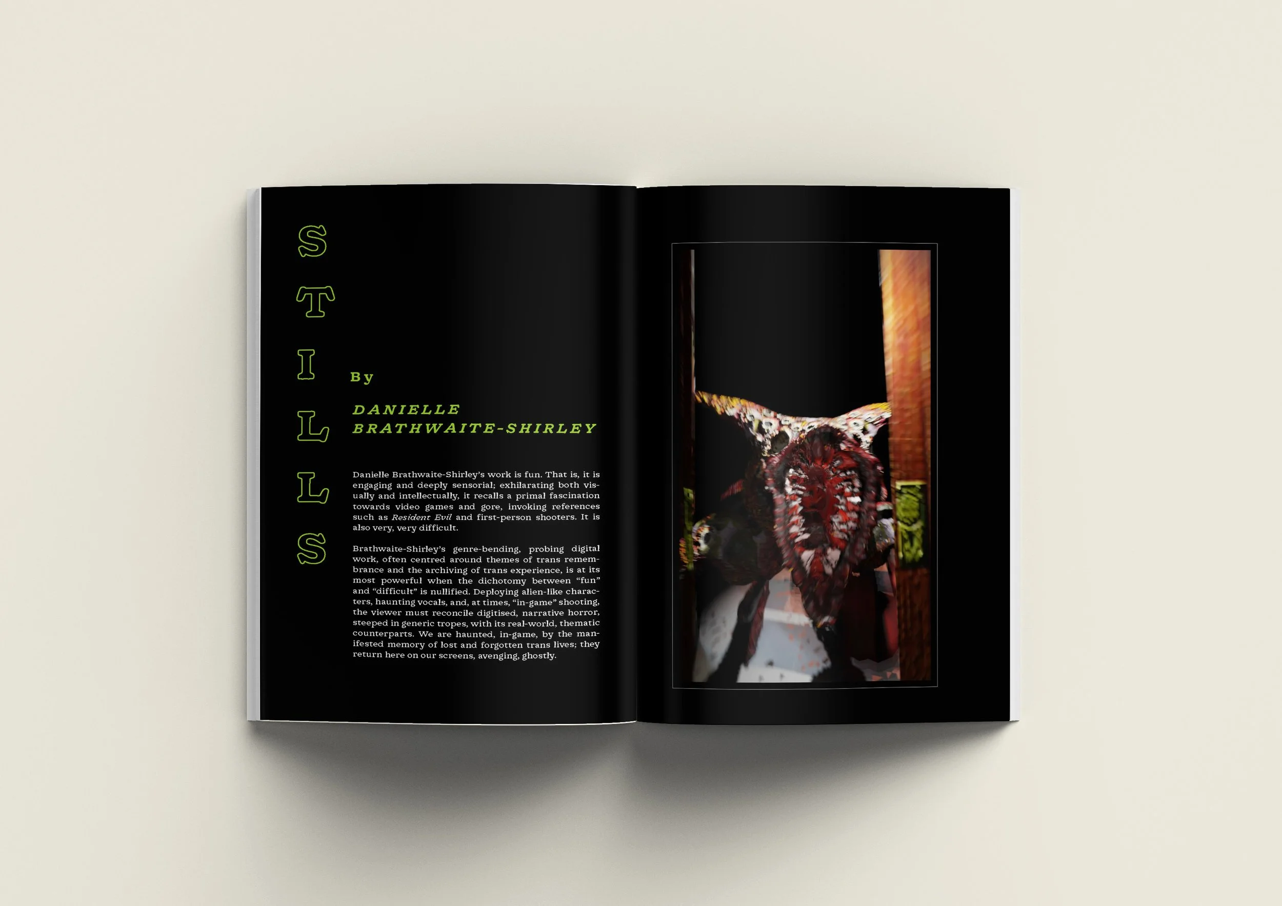 Open magazine with black background pages. Left page has green text titled 'STILLS' by Danielle Brathwaite-Shirley, with a paragraph of description. Right page features a colorful, abstract digital art image of a face and upper body of a figure, with