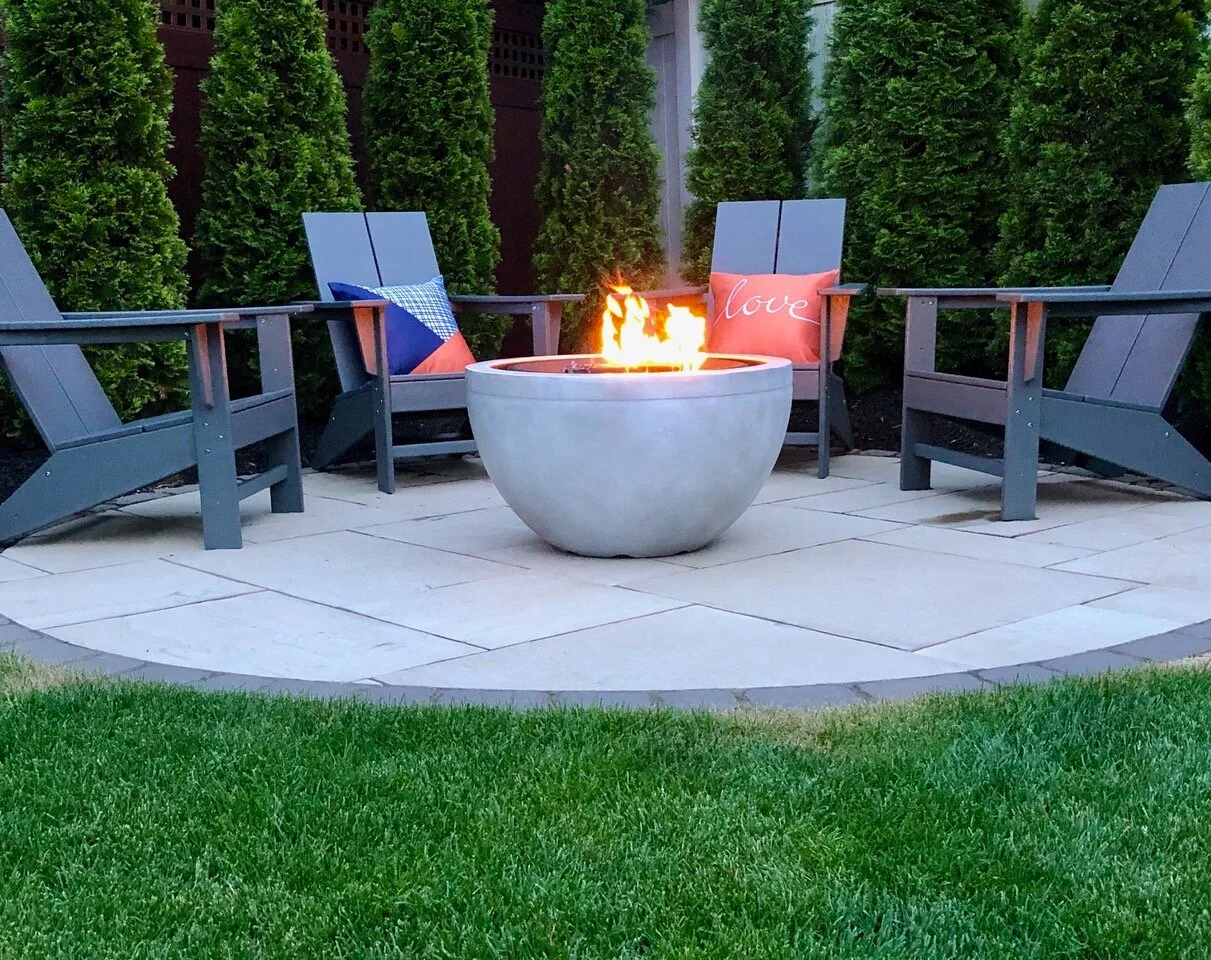 Outdoor living design centered around a modern fire pit and stone patio in Cold Spring Harbor, NY