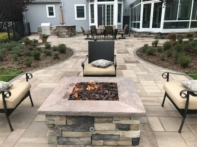 Stone outdoor fireplace with wide hearth seating in a Northport, NY backyard