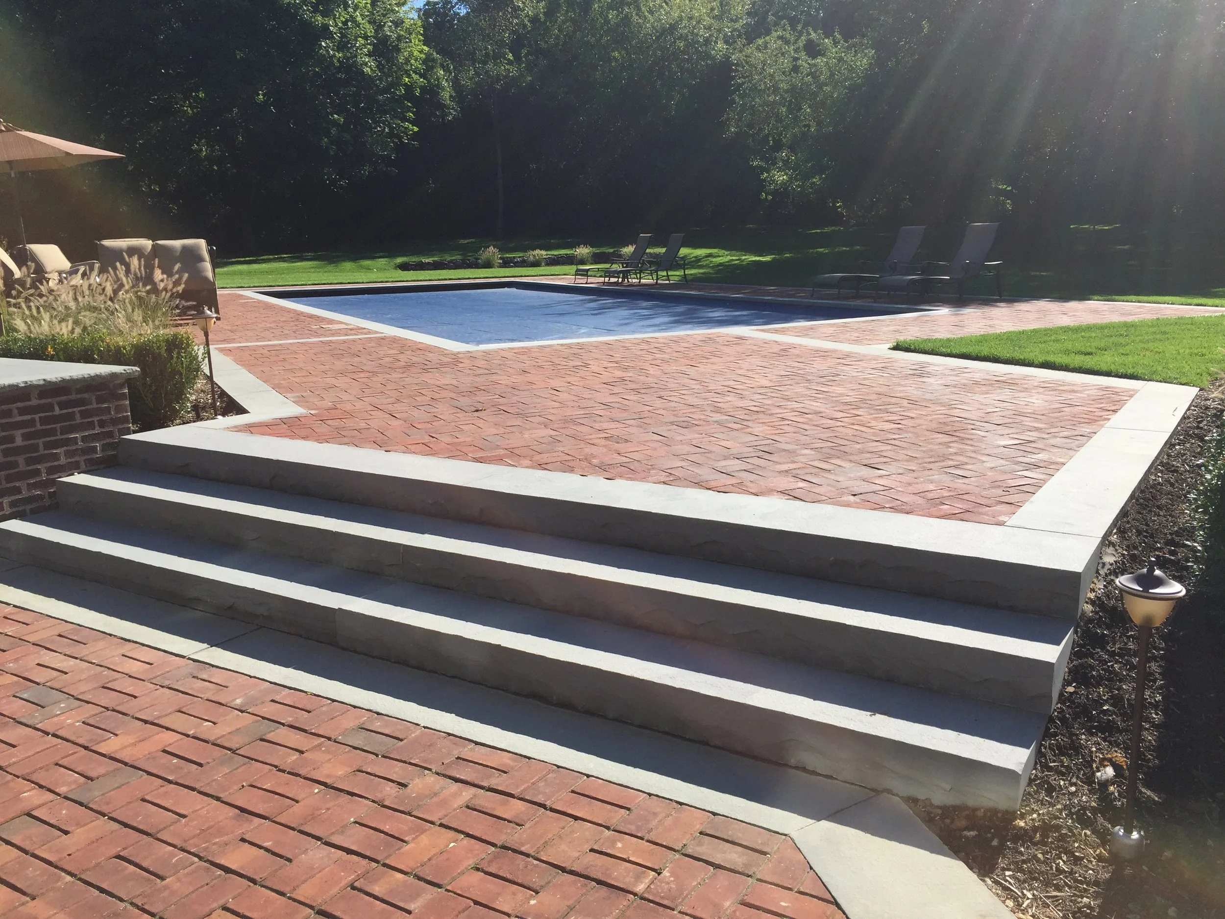 Outdoor fireplace installation paired with lounge seating and hardscape in Port Jefferson, NY