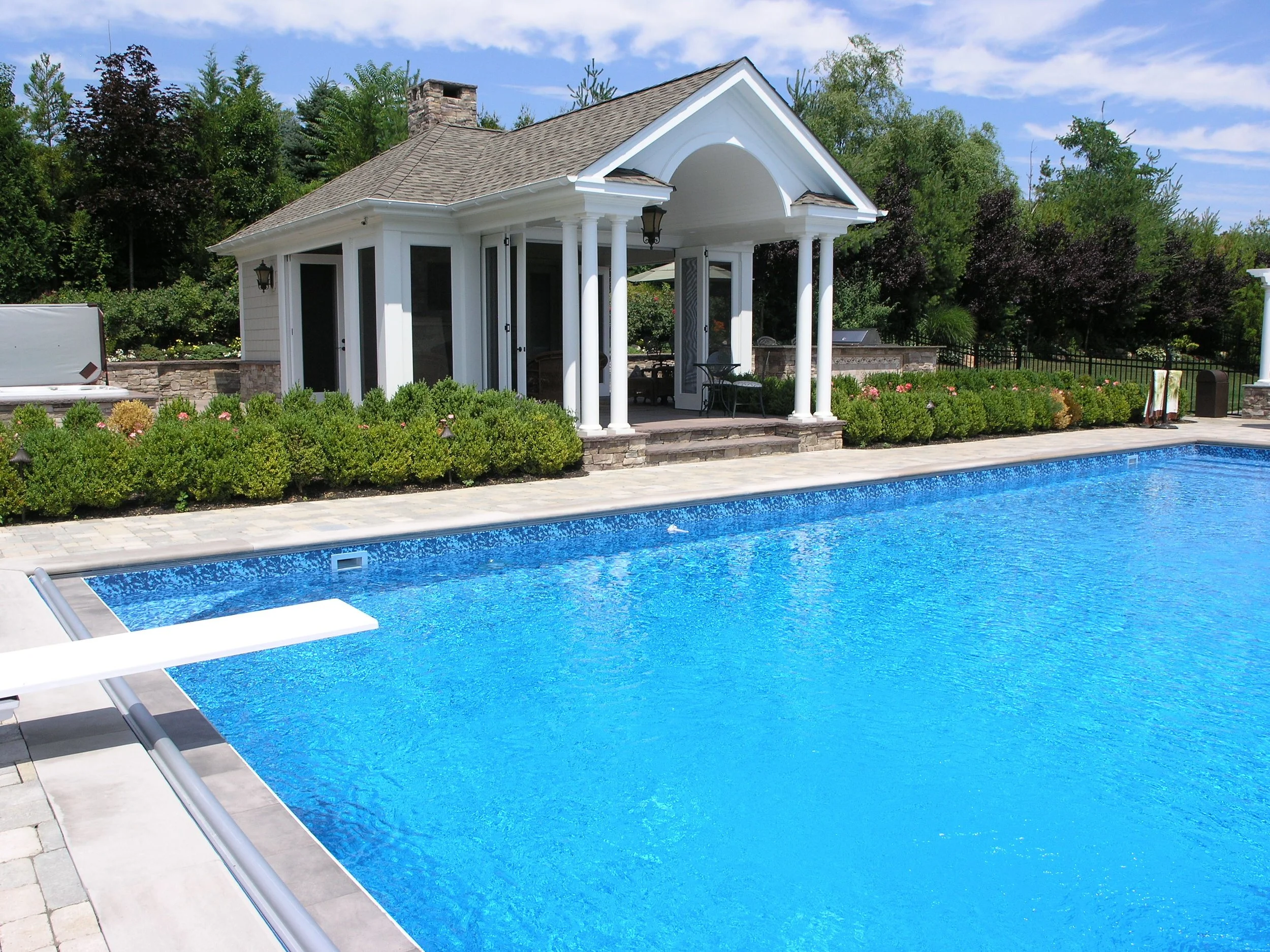 Poolside cabana with classic columns overlooking a custom swimming pool in Setauket, NY