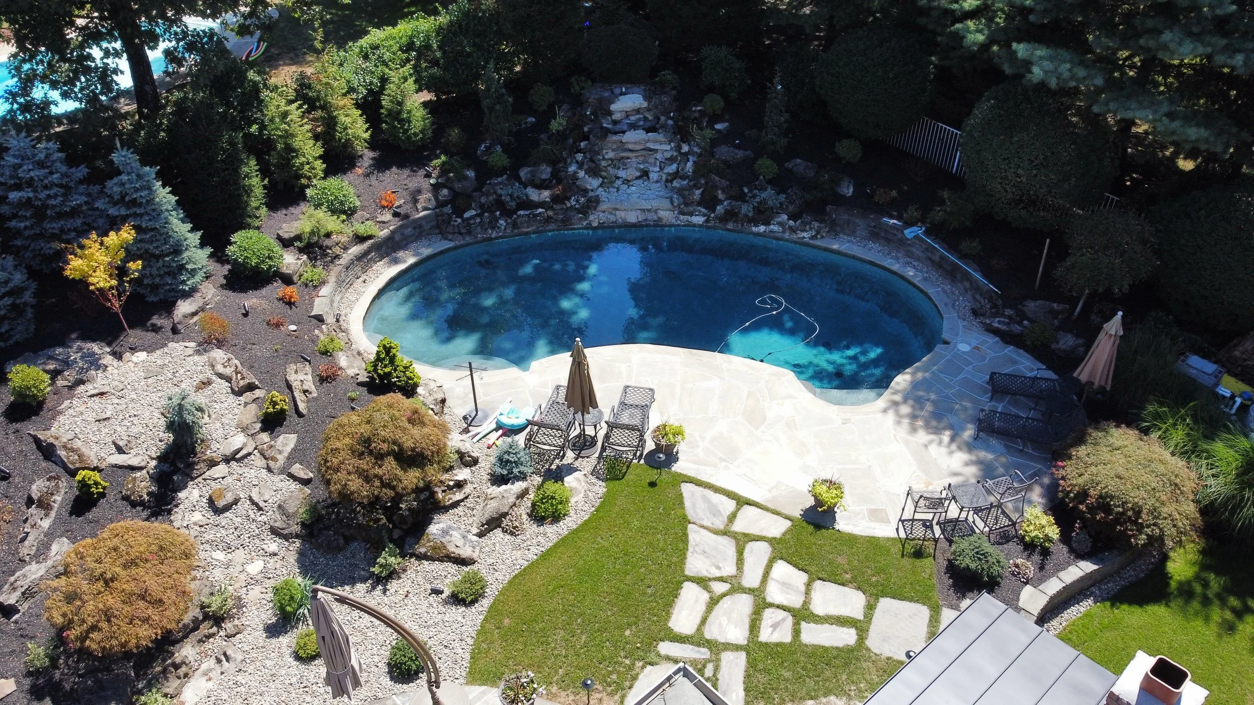 Inground Swimming Pool surrounded by refined hardscape elements in Dix Hills, NY